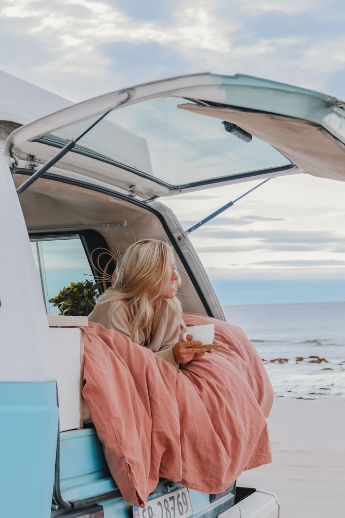 Femme install&eacute;e dans son van am&eacute;nag&eacute; face &agrave; la mer
