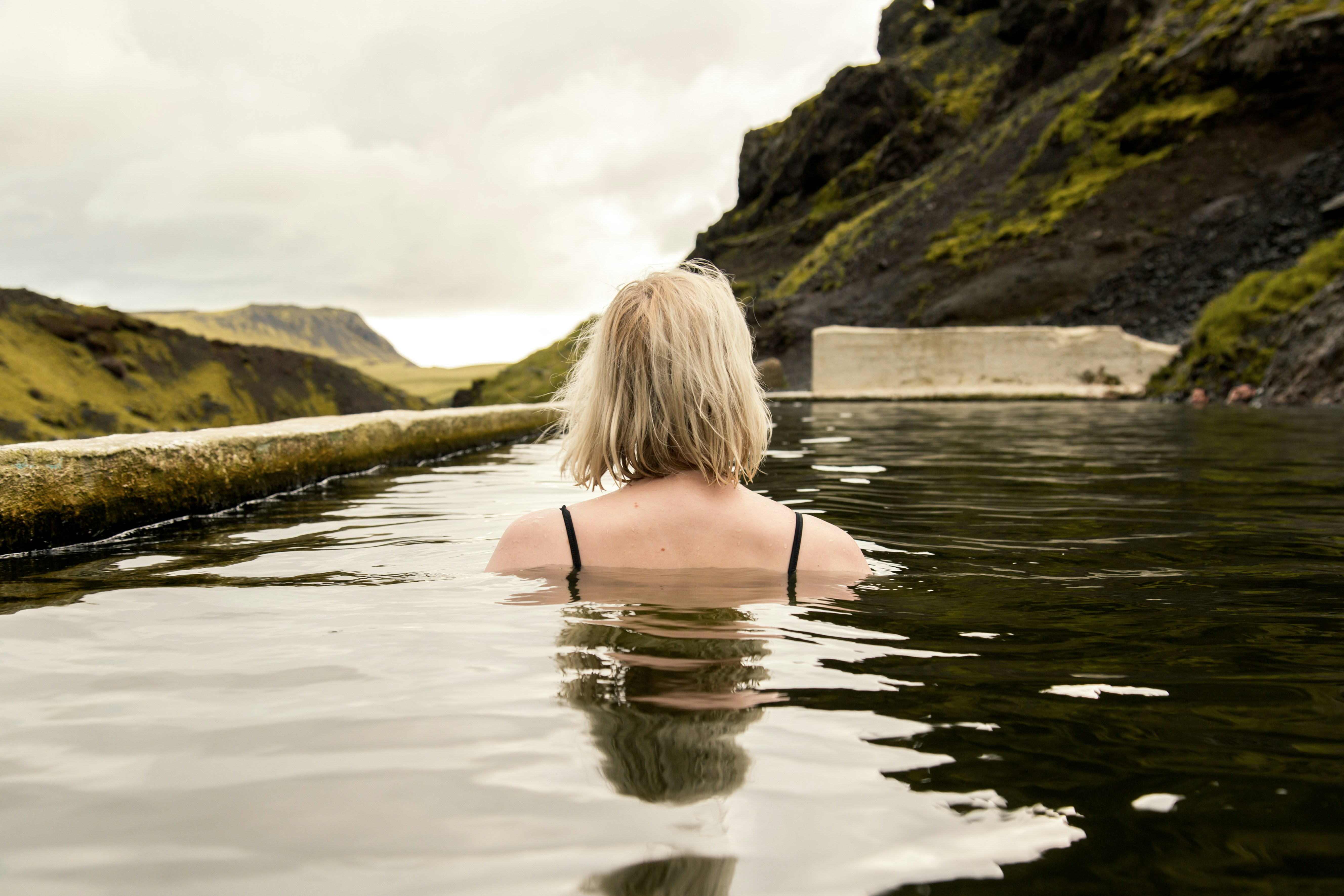 A woman is sitting in a body of water, Woman in a geothermal pool in Iceland