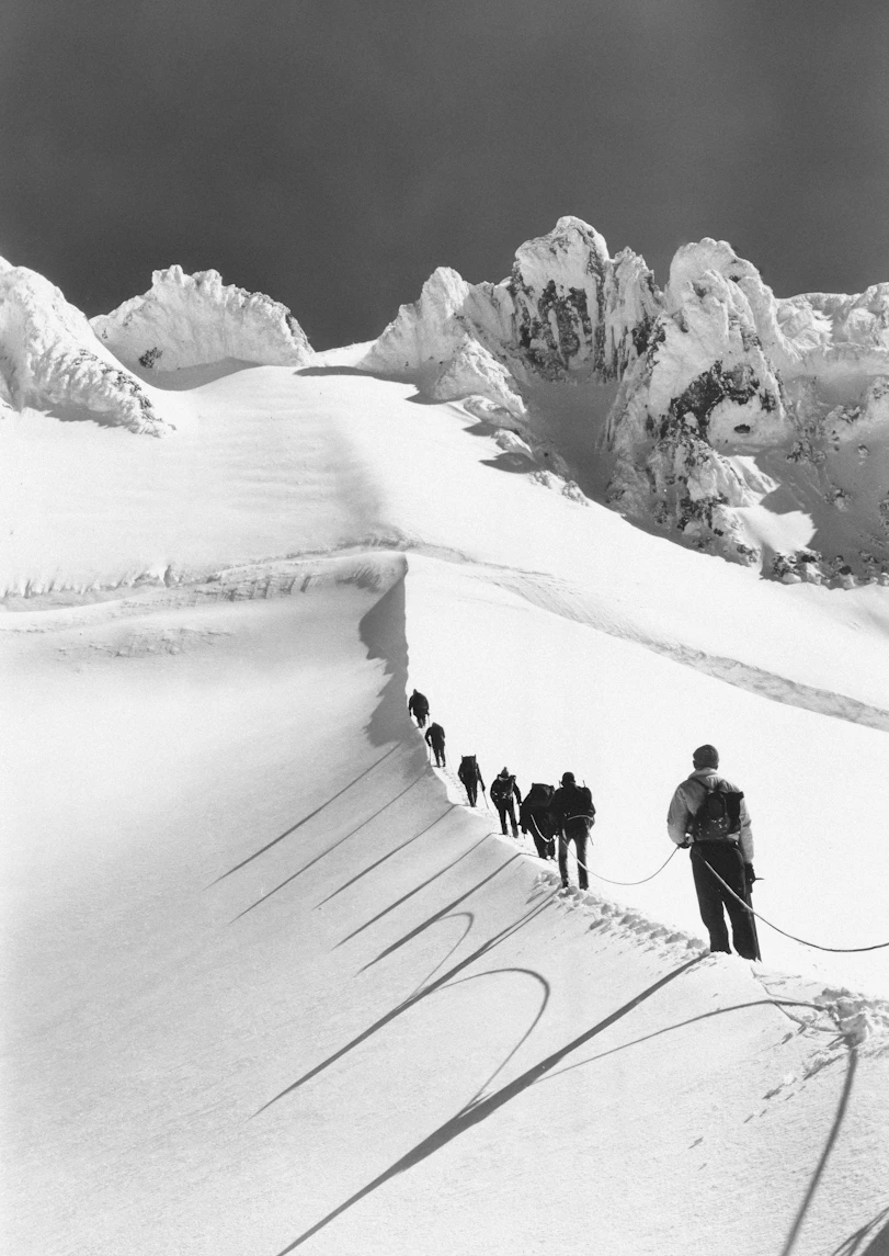A group of people walking up a snow covered slope