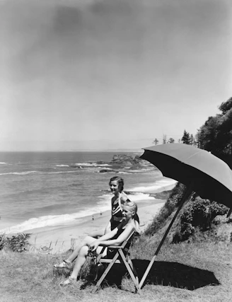 Two women relaxing by the ocean under an umbrella