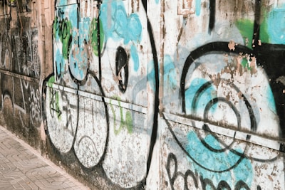 A man walking down a sidewalk next to a wall covered in graffiti