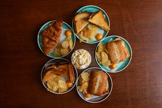 A wooden table topped with four plates of food