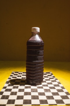A plastic bottle sitting on top of a chess board