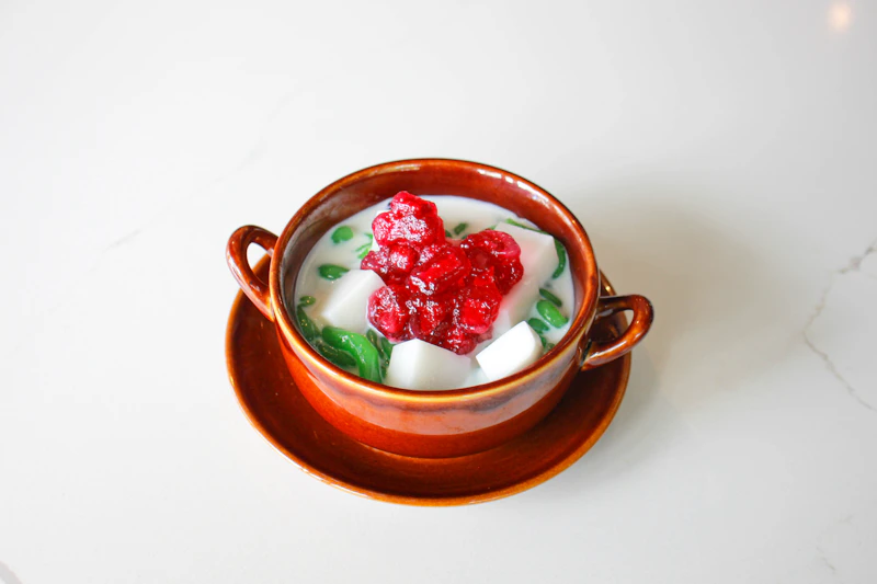 A bowl of chè, layered with jellies and fresh fruit in coconut milk