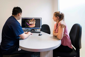 A man and a woman sitting at a table looking at a computer screen