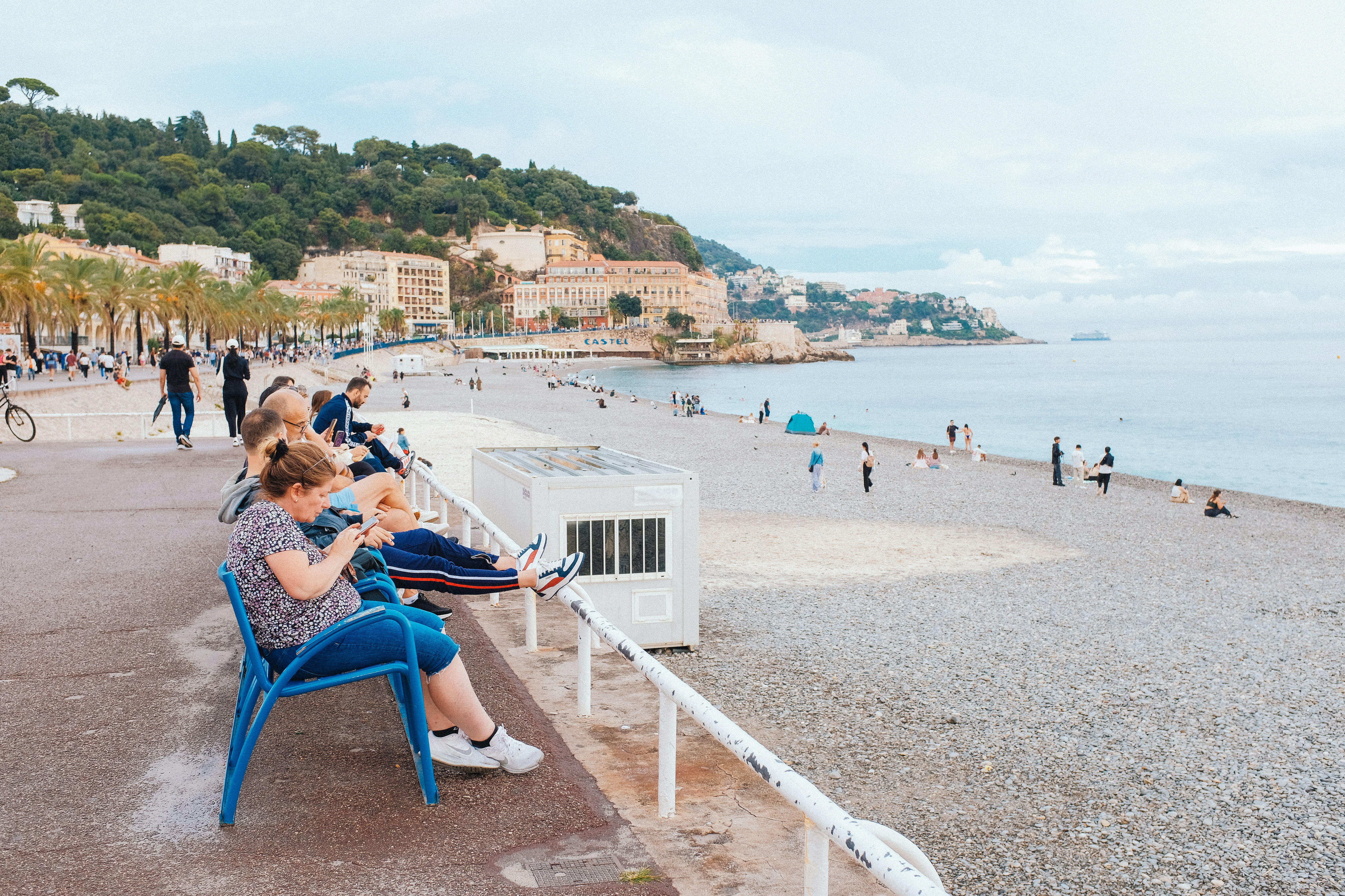 A woman sitting on a blue chair next to the ocean