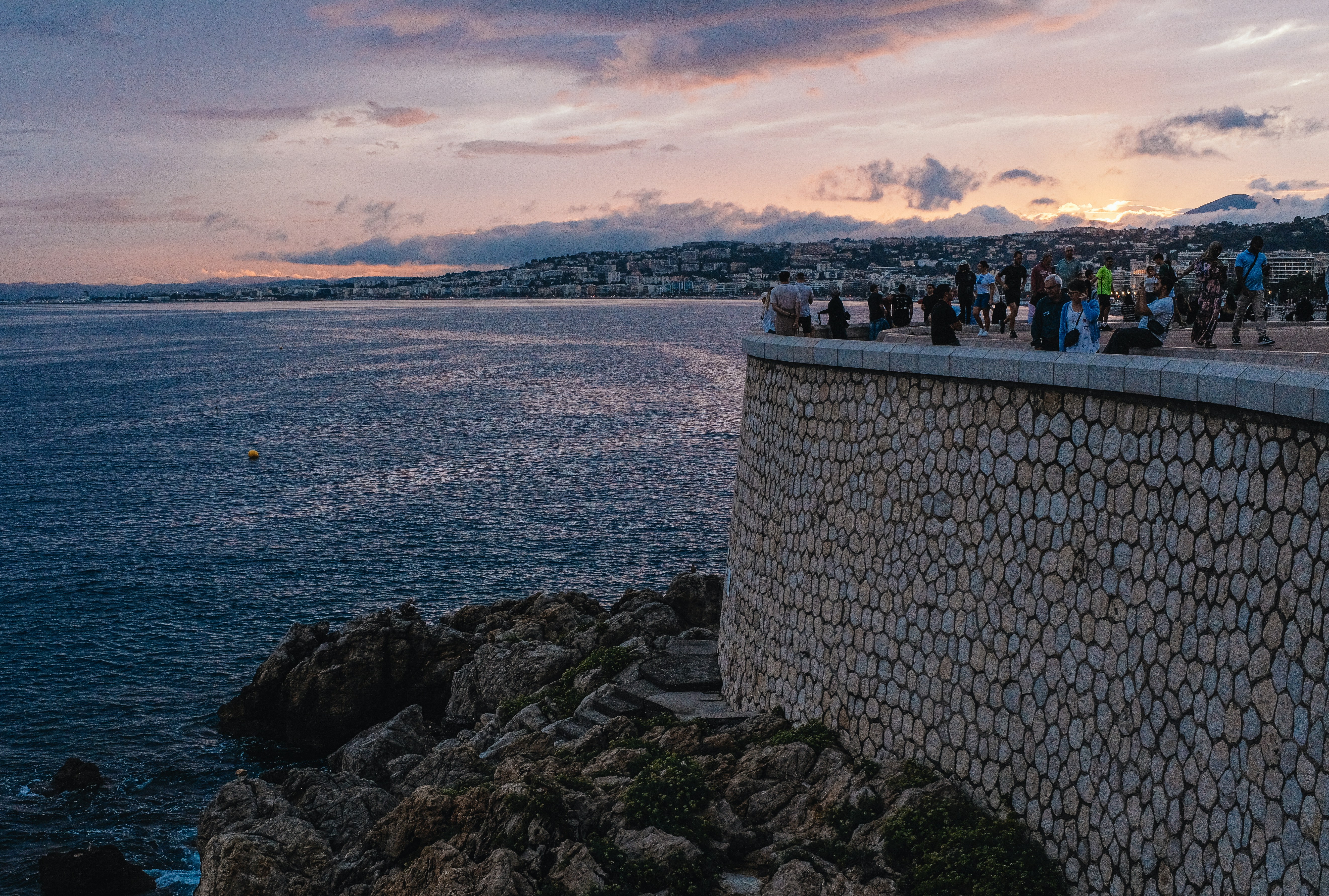 A group of people standing on top of a cliff next to the ocean