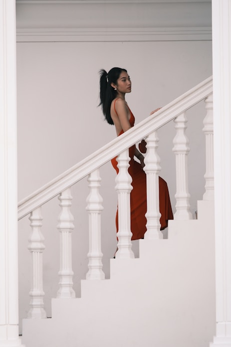 A woman in a red dress standing on a stair case