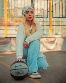A woman sitting on the ground with a basketball