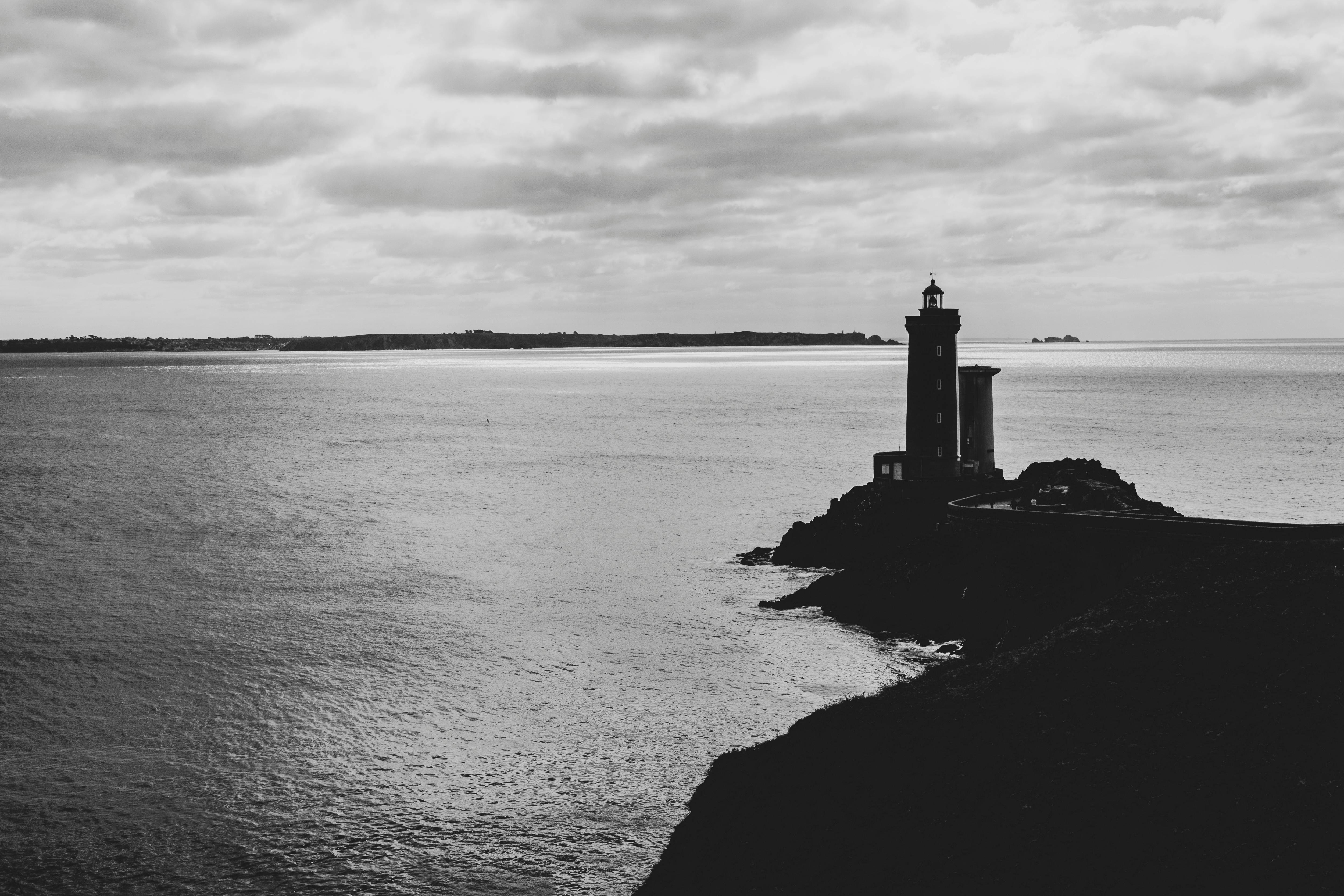 A black and white photo of a lighthouse in the ocean