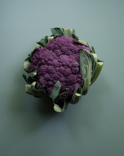 A close up of a purple cauliflower on a gray background