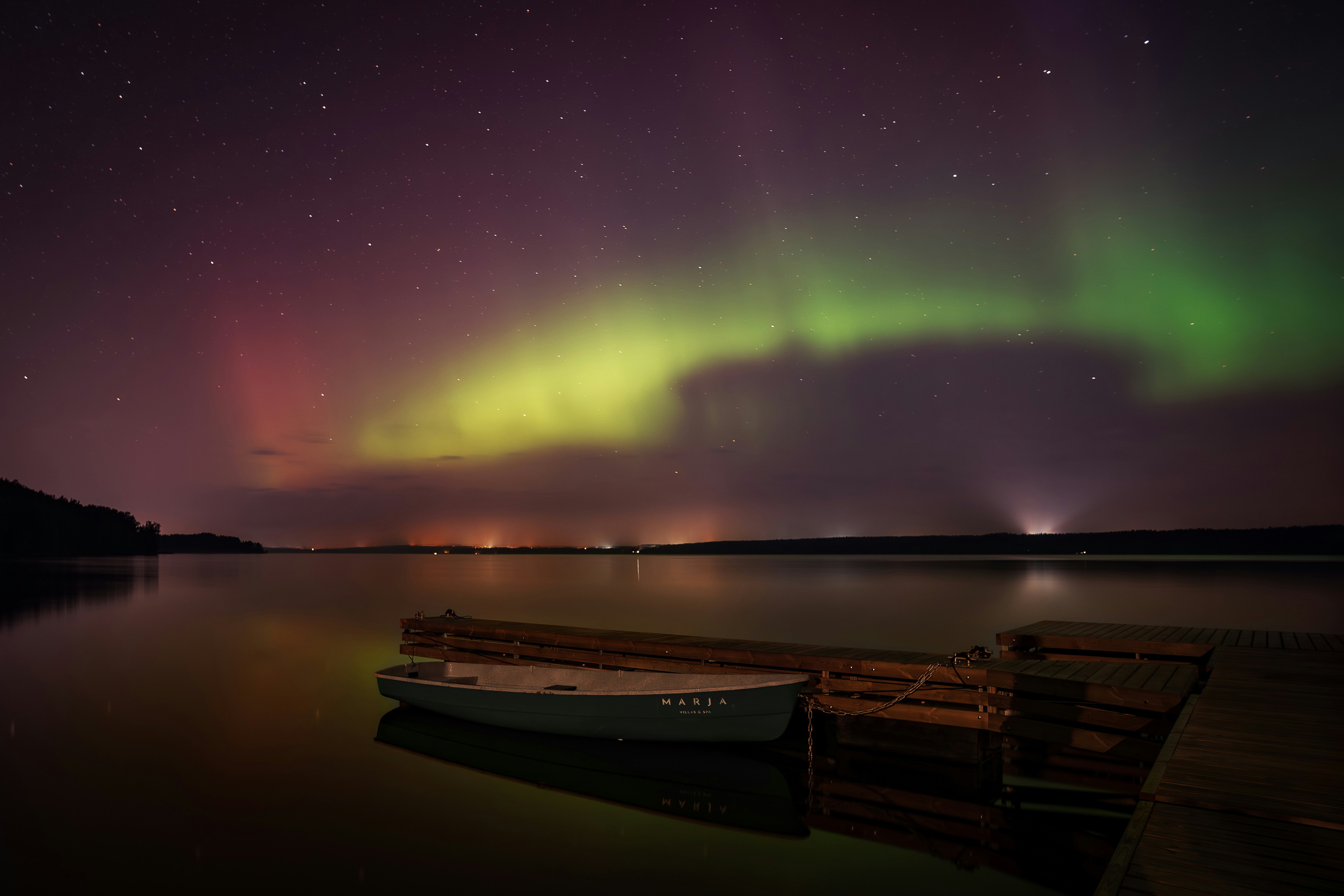 A boat sitting on top of a lake under a purple sky