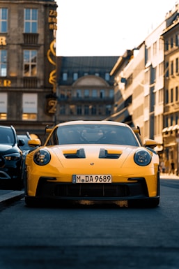A yellow sports car driving down a city street