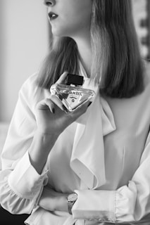 A woman in a white shirt holding a bottle of perfume