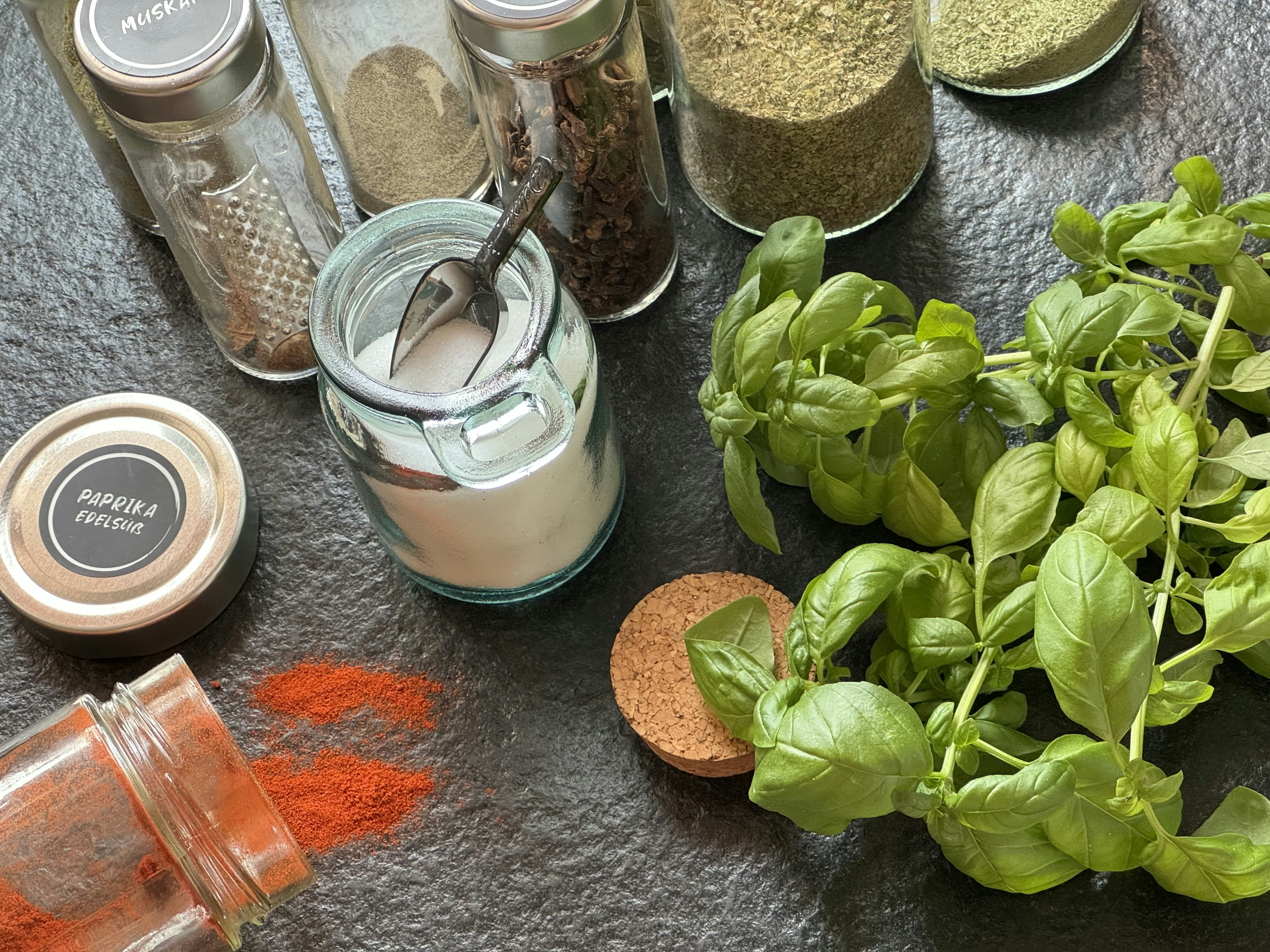 Fresh and dried basil leaves arranged on white marble surface with natural light