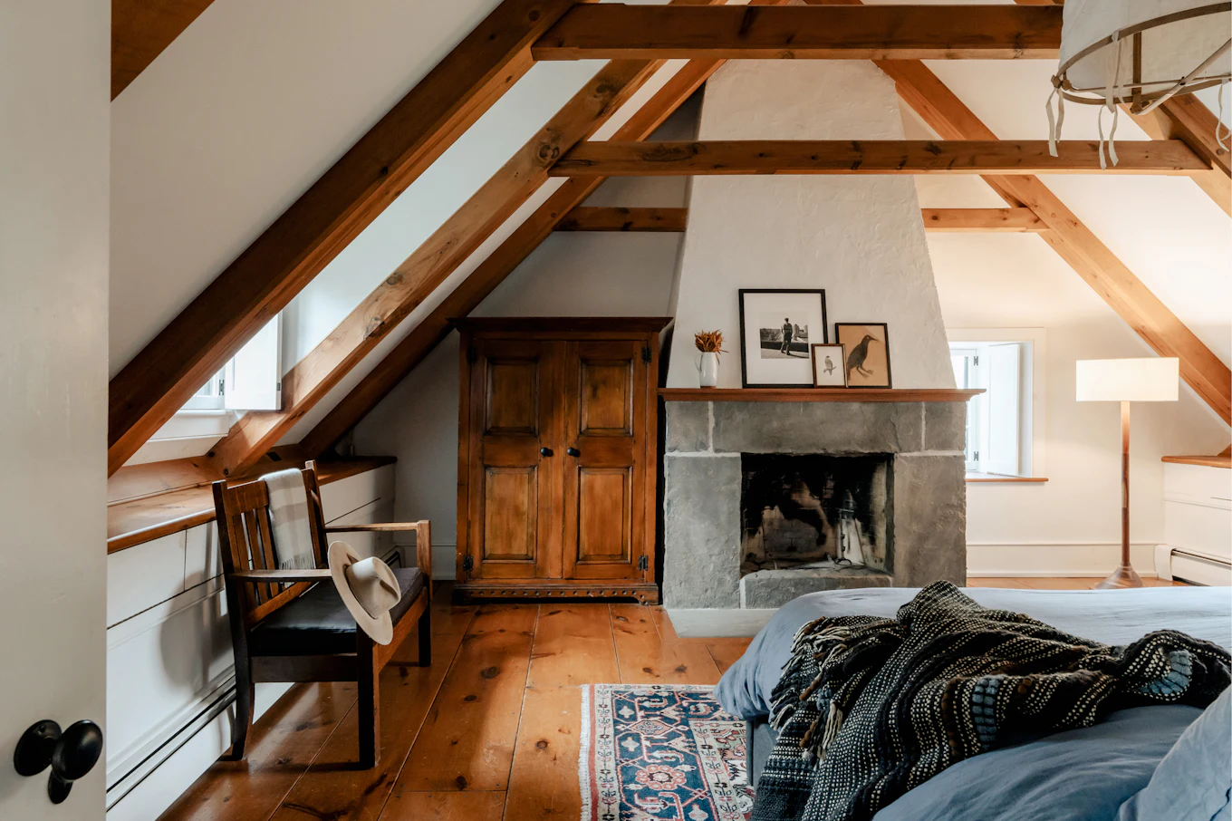 The attic room, roof beams overhead and the bed made up under them