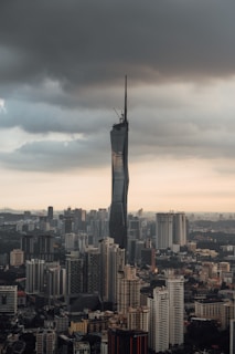 A very tall building towering over a city under a cloudy sky