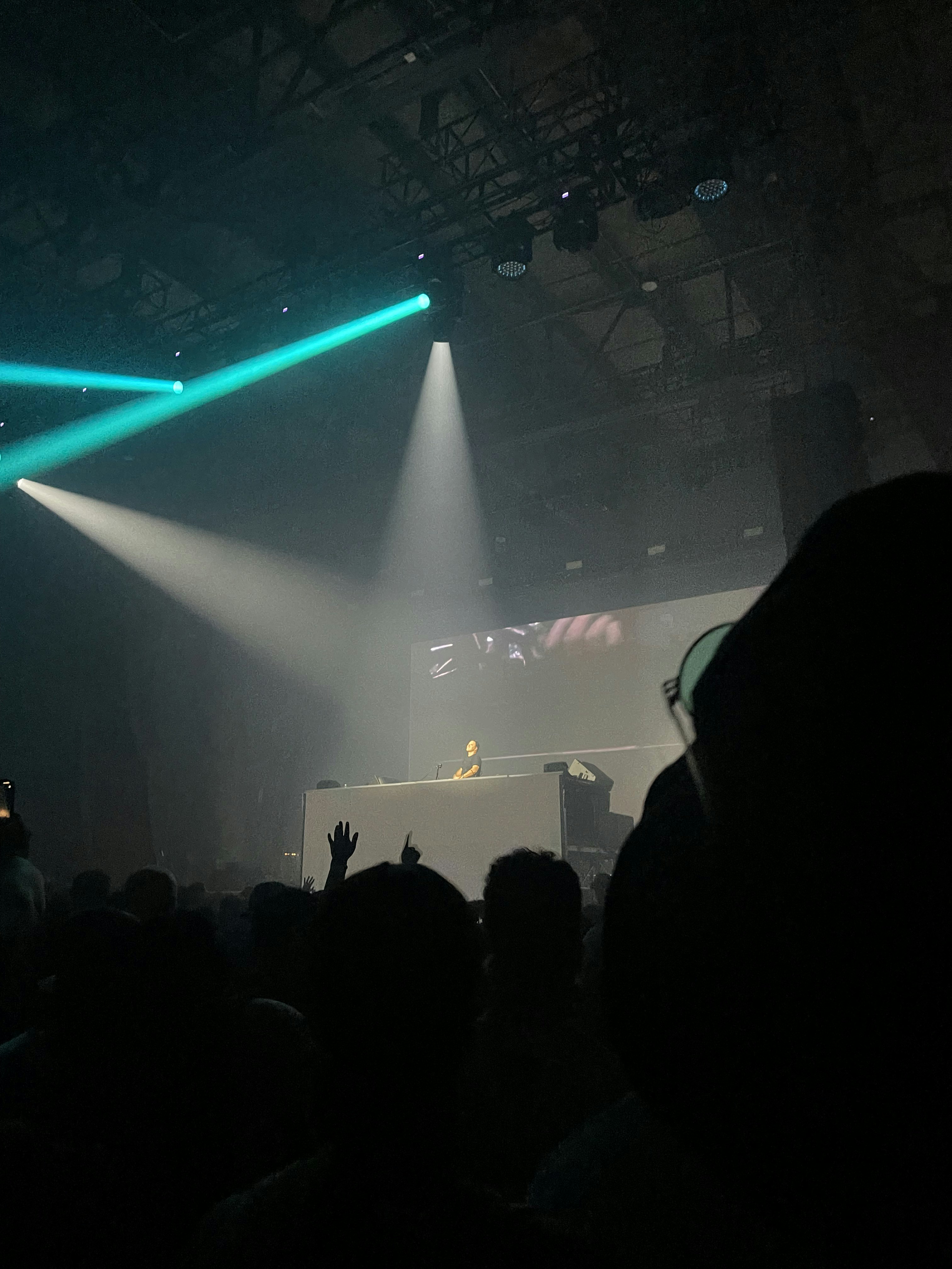 DJ professionnel avec équipement haut de gamme et lumières stroboscopiques bleues et blanches, crowd en arrière-plan