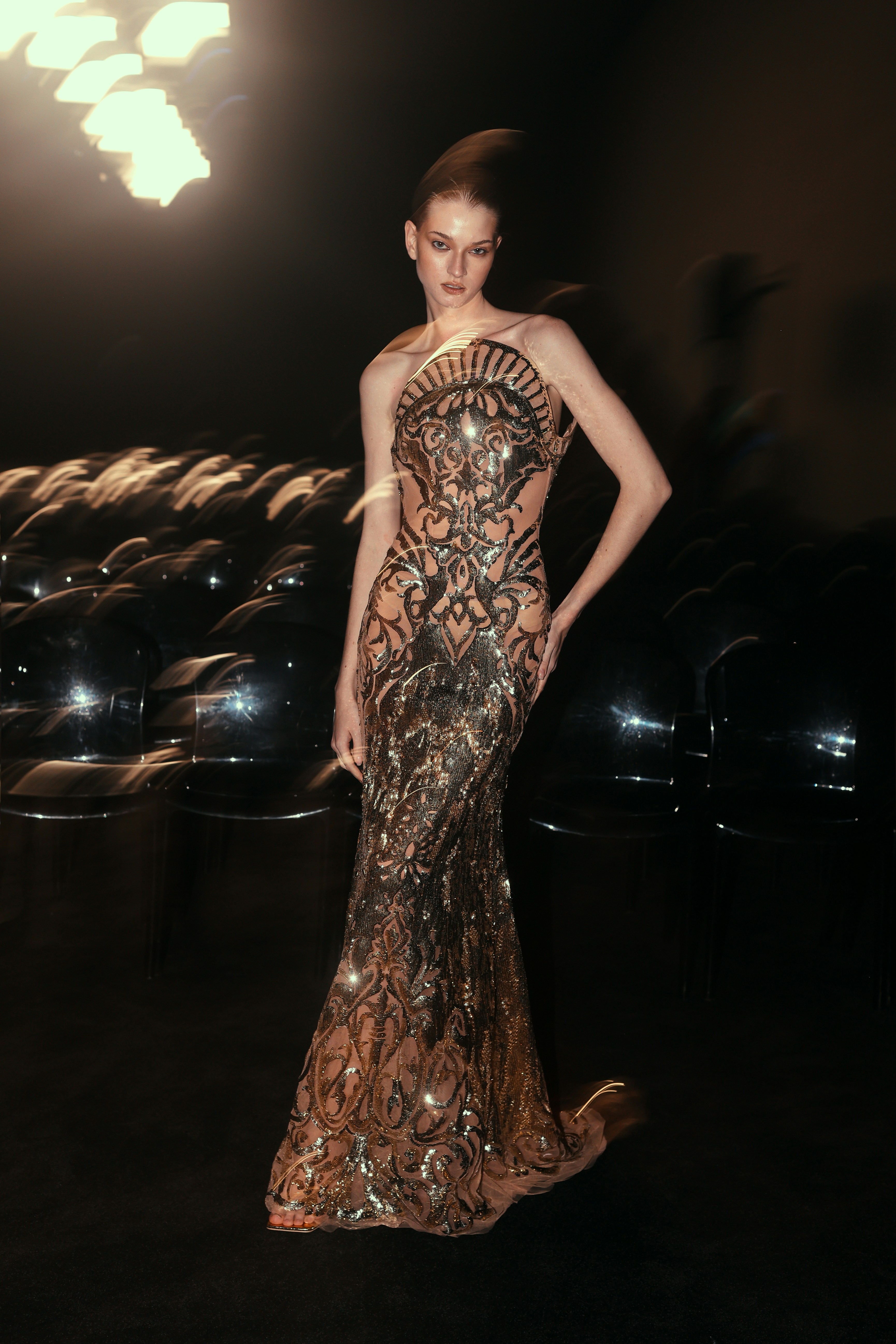 A woman in a long dress standing in a dark room