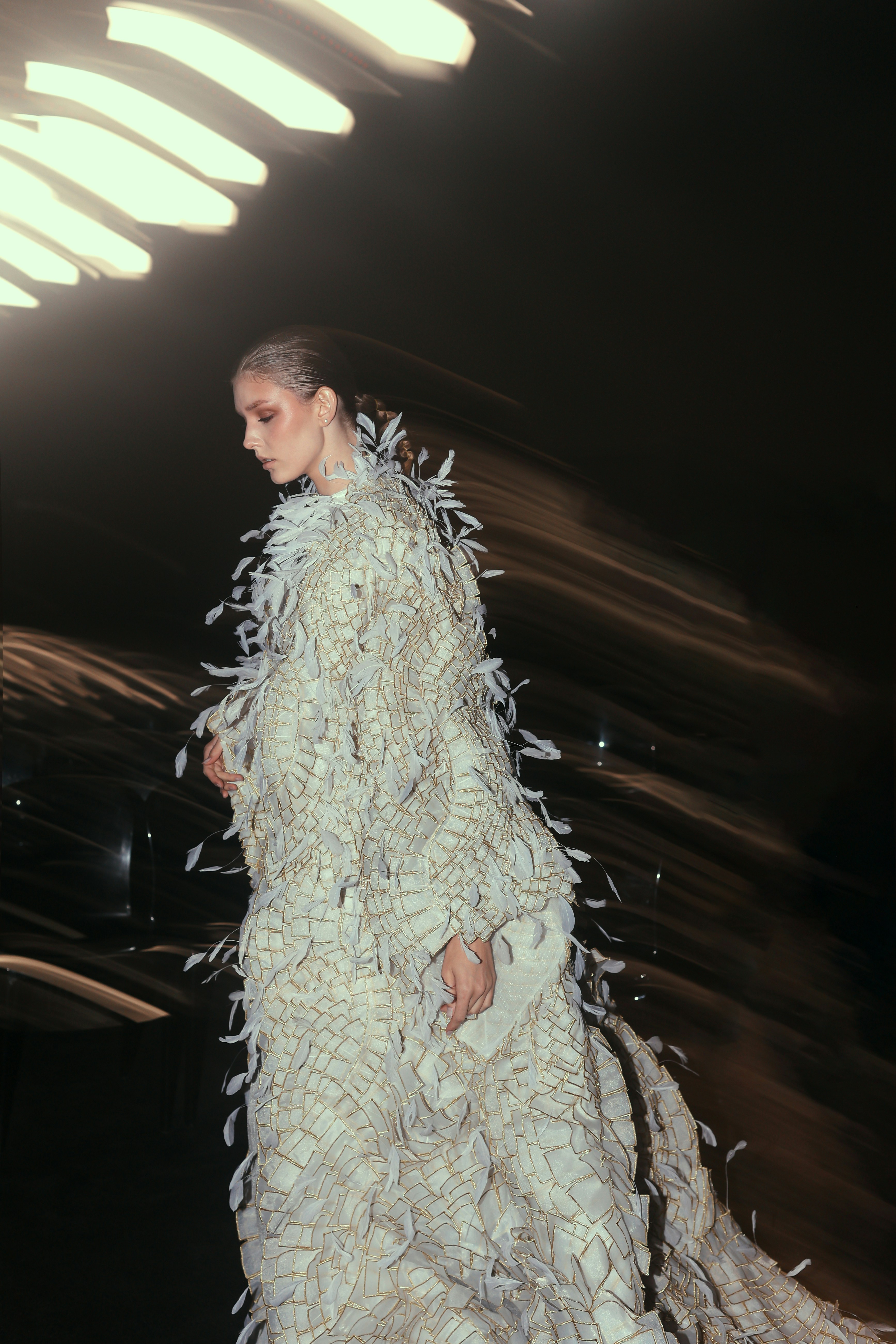 A woman in a white dress walking down a runway