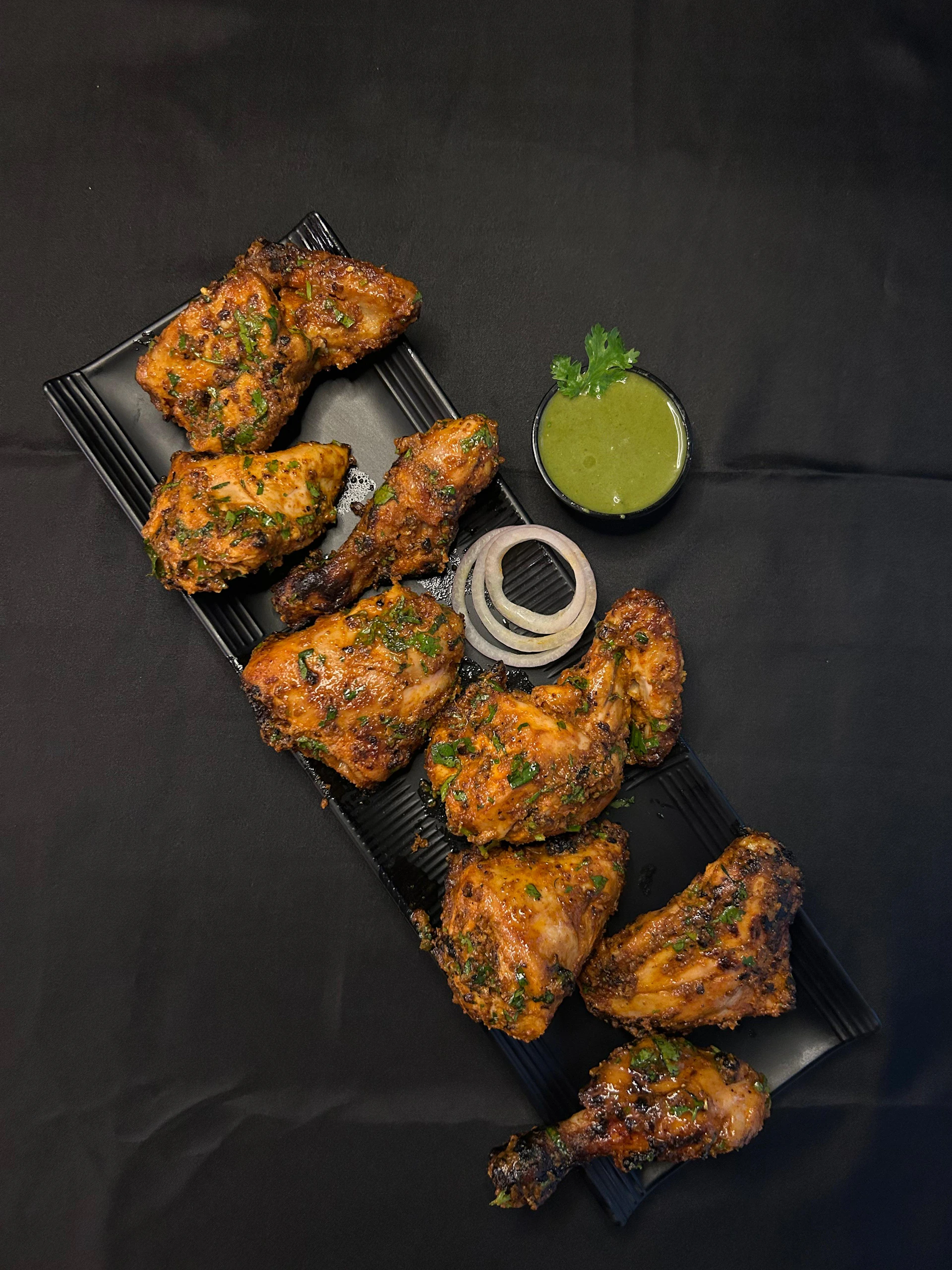 A tray of chicken wings with a side of dipping sauce