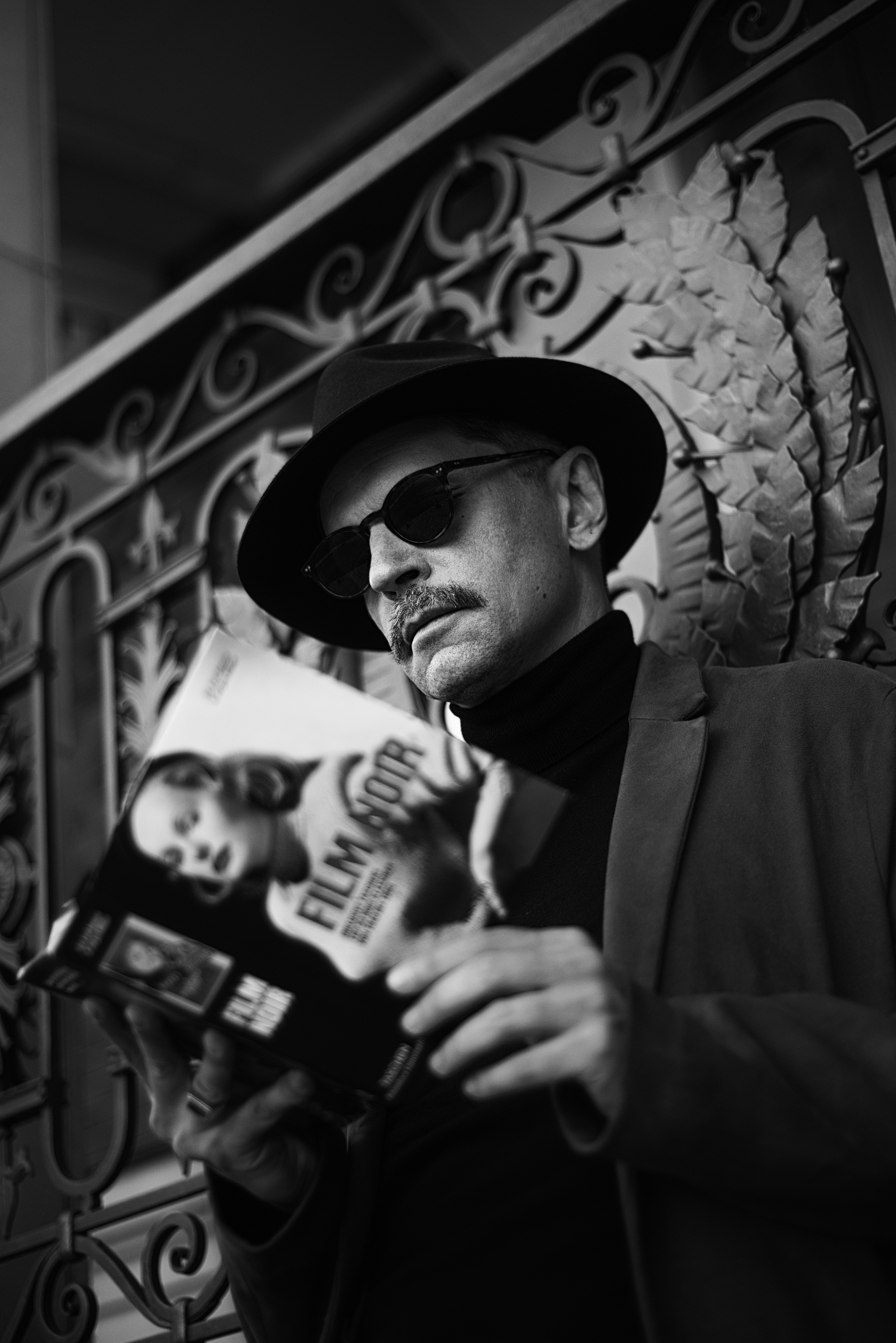 Un homme avec un chapeau et des lunettes de soleil tenant un téléphone portable