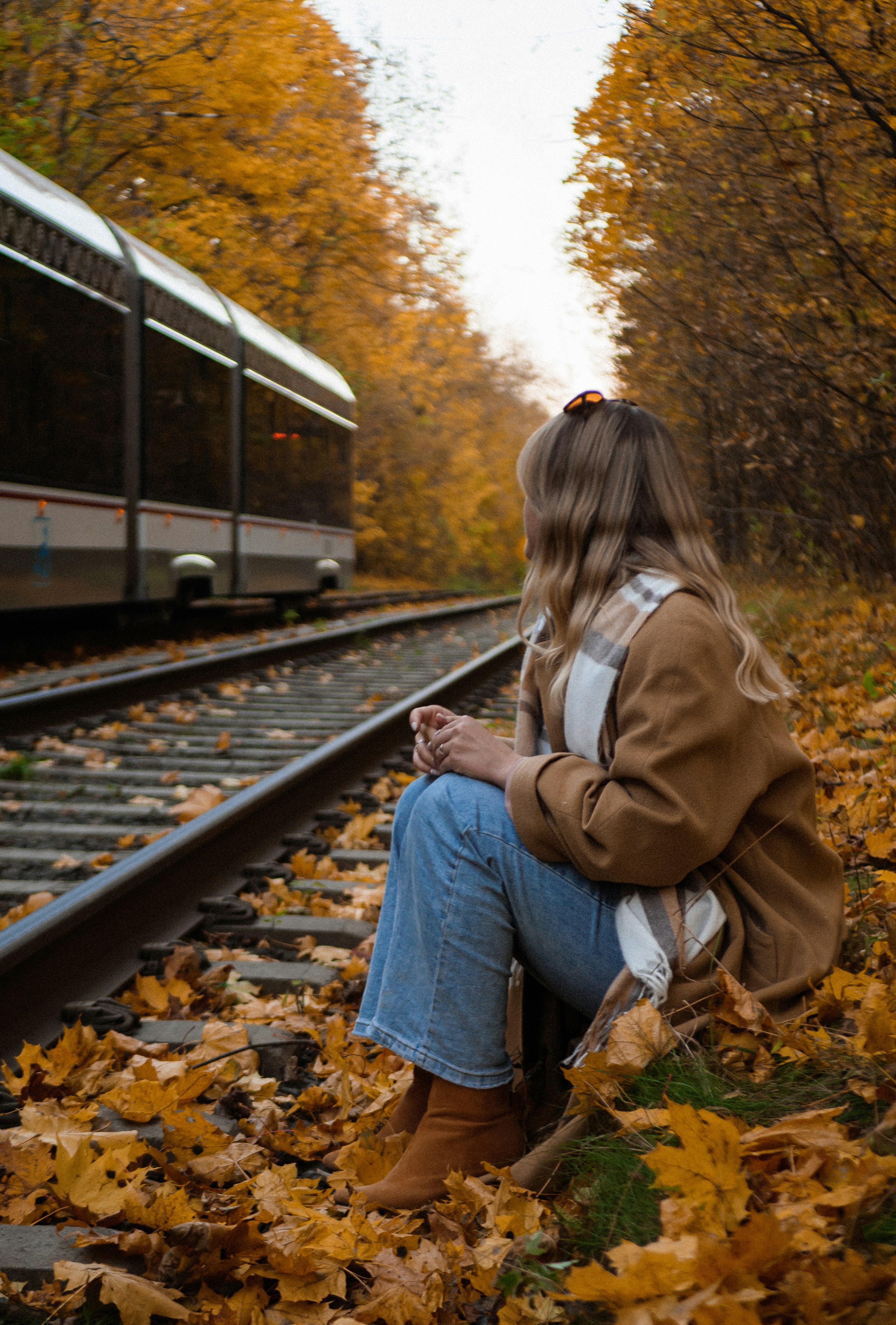 Una mujer sentada en una vía de tren junto a un tren
