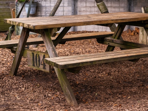 A wooden picnic table sitting in the dirt