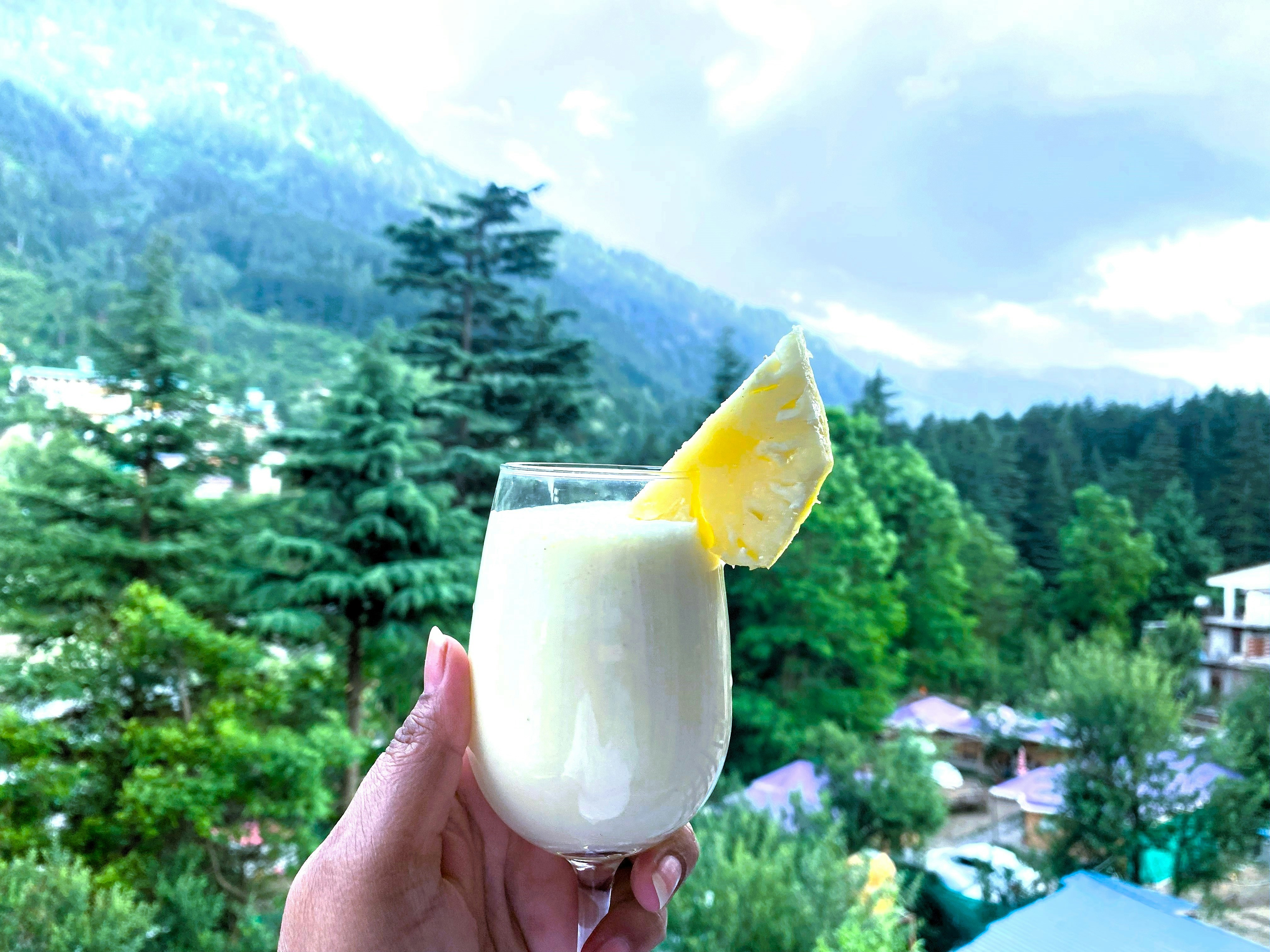 Thick creamy smoothie in a glass with fresh fruit garnish, bright sunny kitchen background