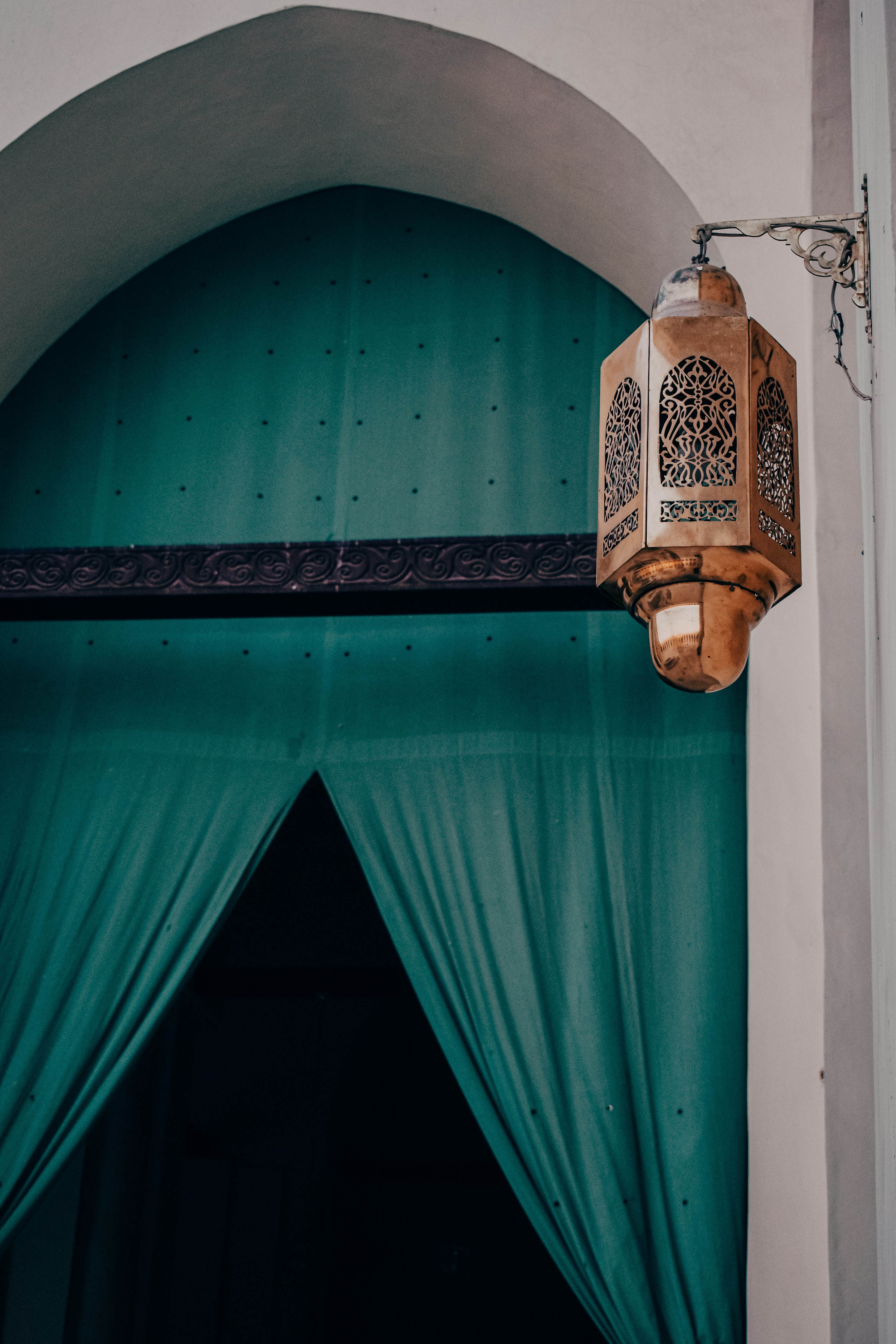 A window with a green curtain and a lantern hanging from it