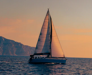 A sailboat sailing in the ocean at sunset