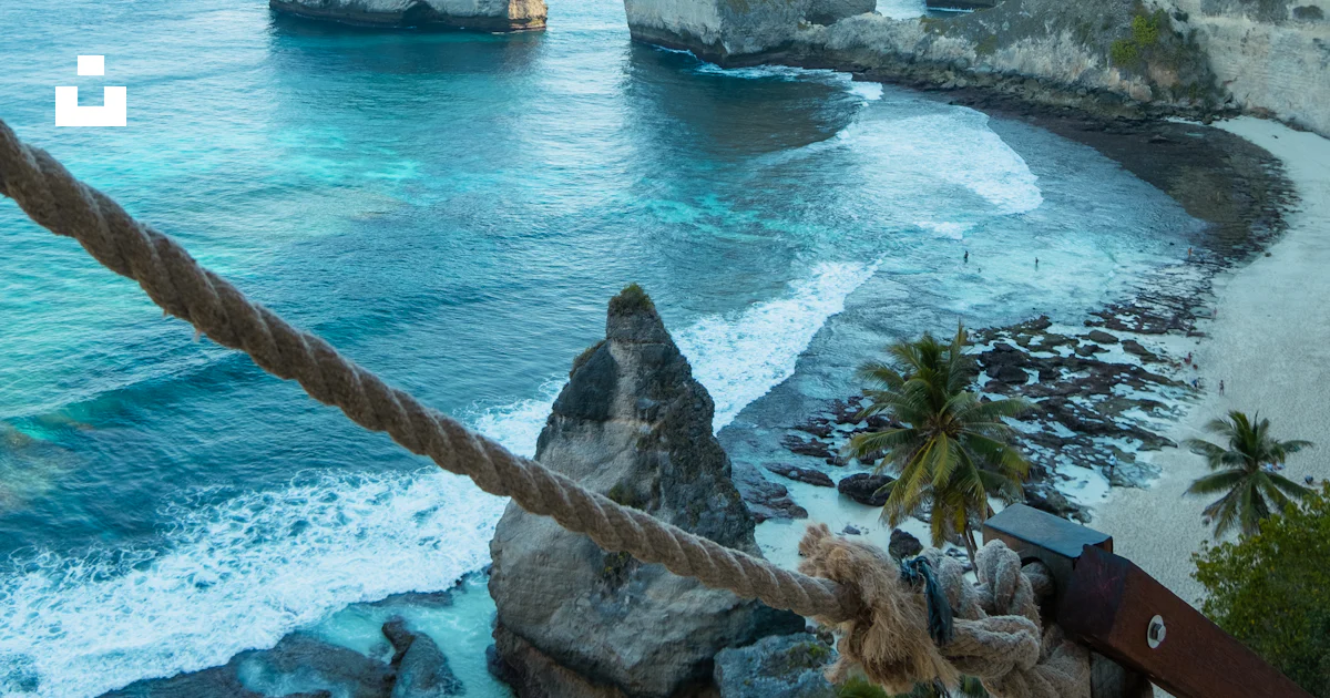 A rope hanging from the side of a cliff next to the ocean photo – Free ...