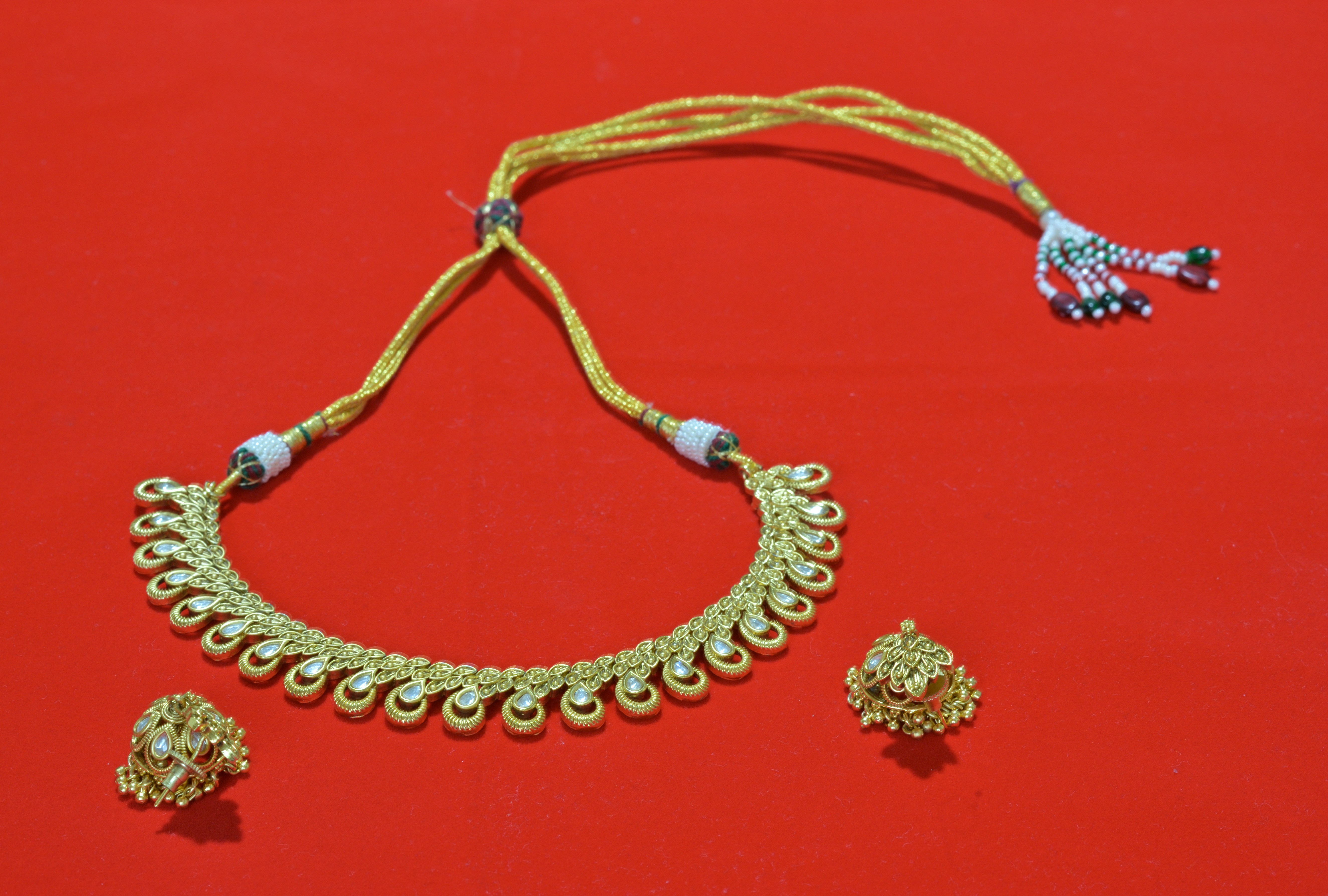 A necklace and earrings on a red surface