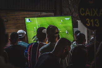 A group of people watching a cricket game on TV, resturant settings