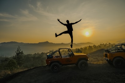 A man jumping off of a jeep into the air