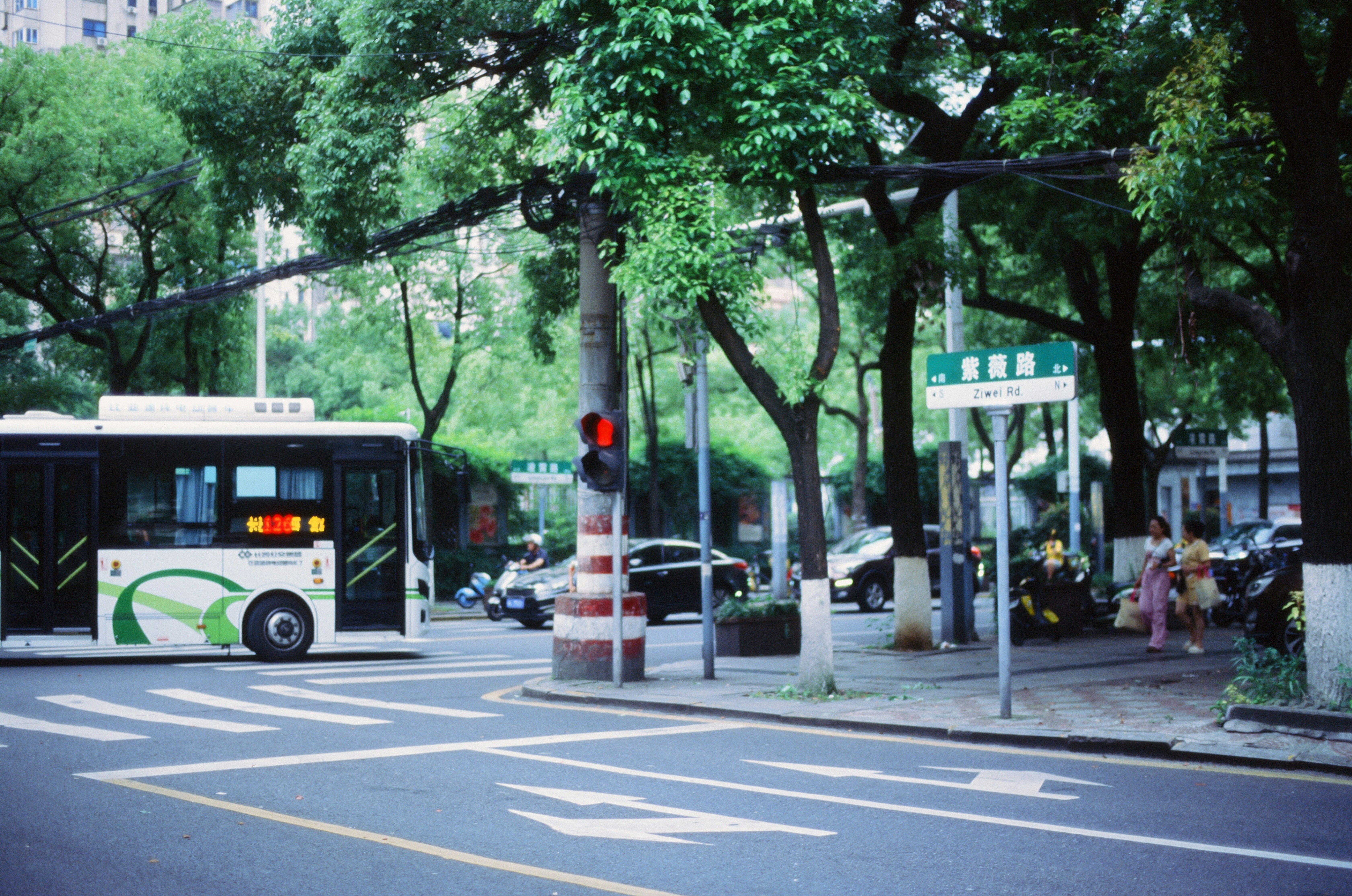 A city bus driving down a street next to a traffic light