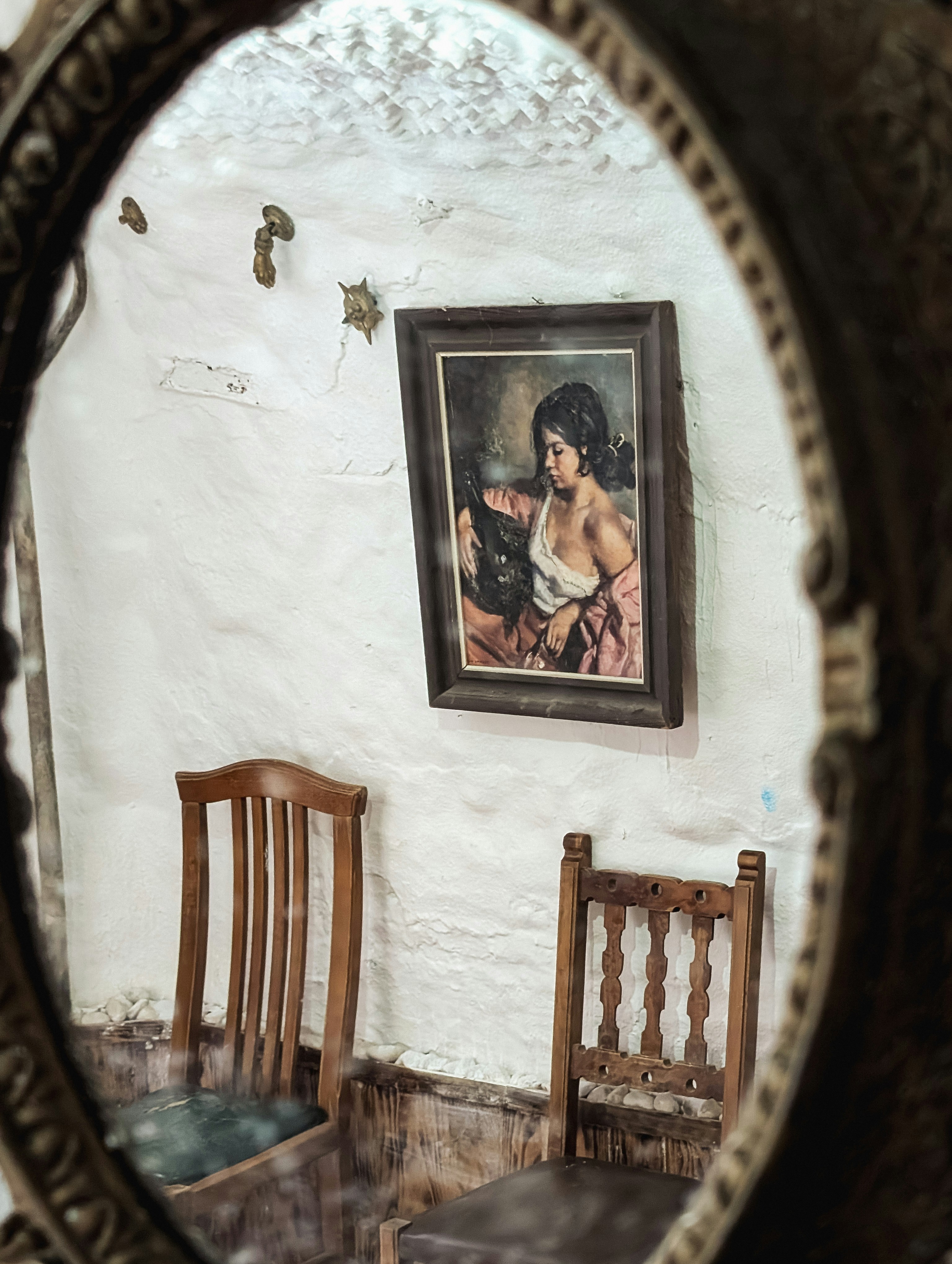 A mirror reflecting a picture of a woman on a wall