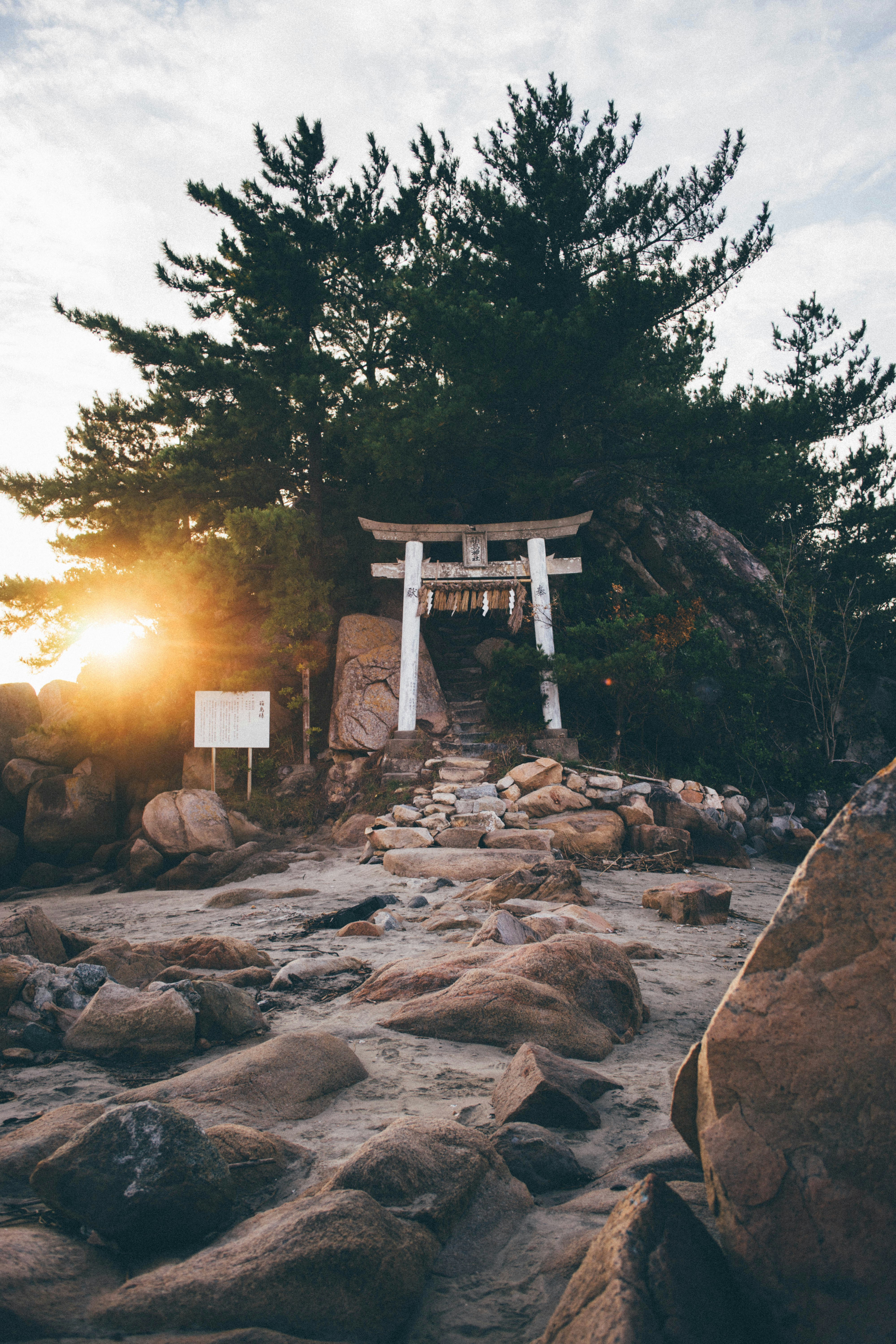 The sun is setting on a rocky beach