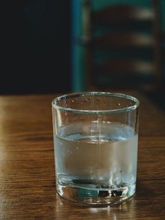 A glass of water sitting on top of a wooden table