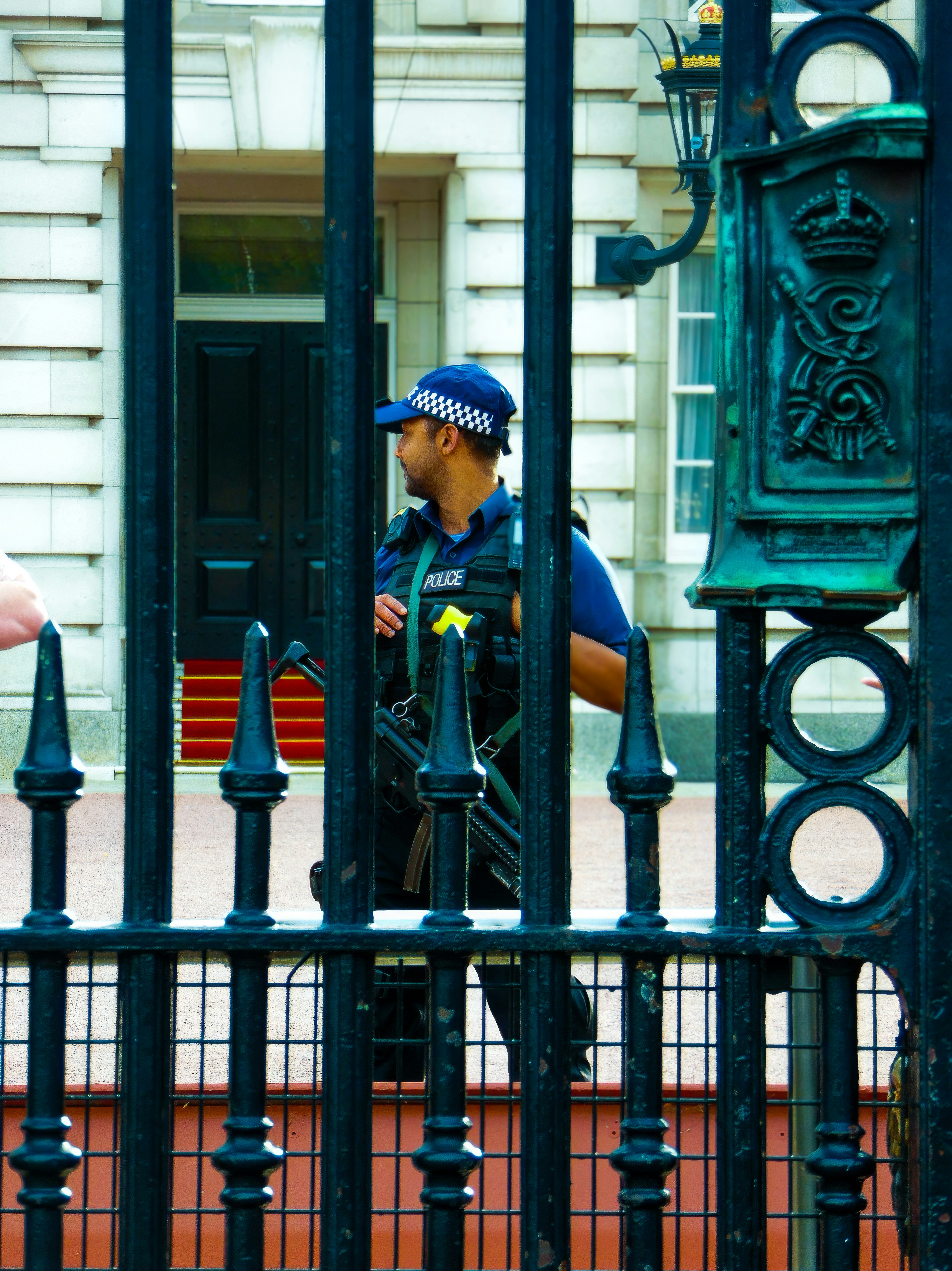 A police officer standing behind a gate in front of a building