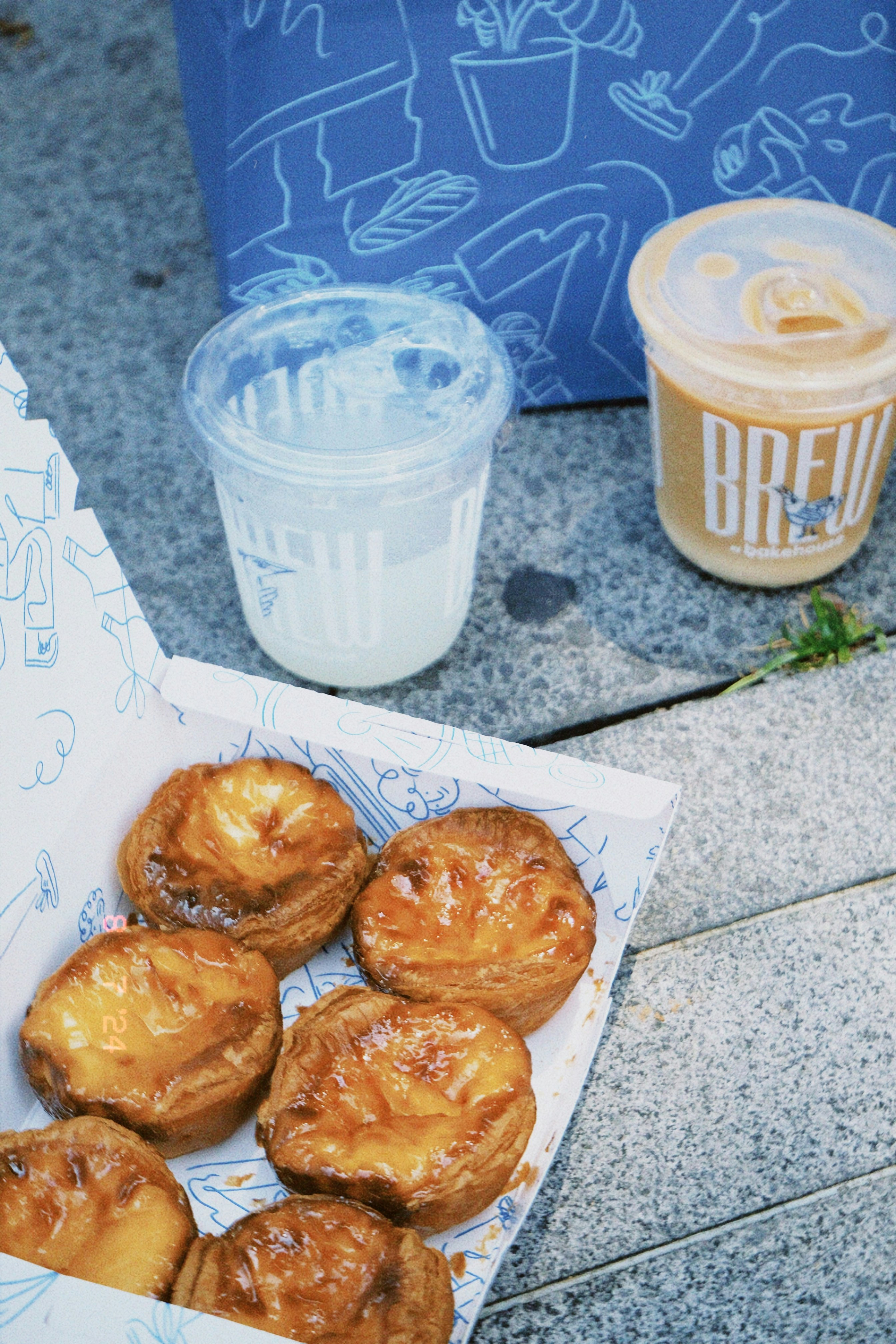 A box of doughnuts next to a cup of coffee