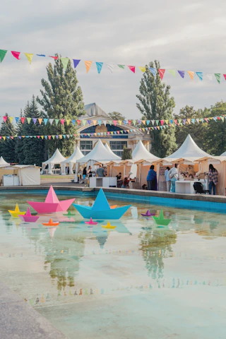 A group of people standing next to a pool filled with paper boats