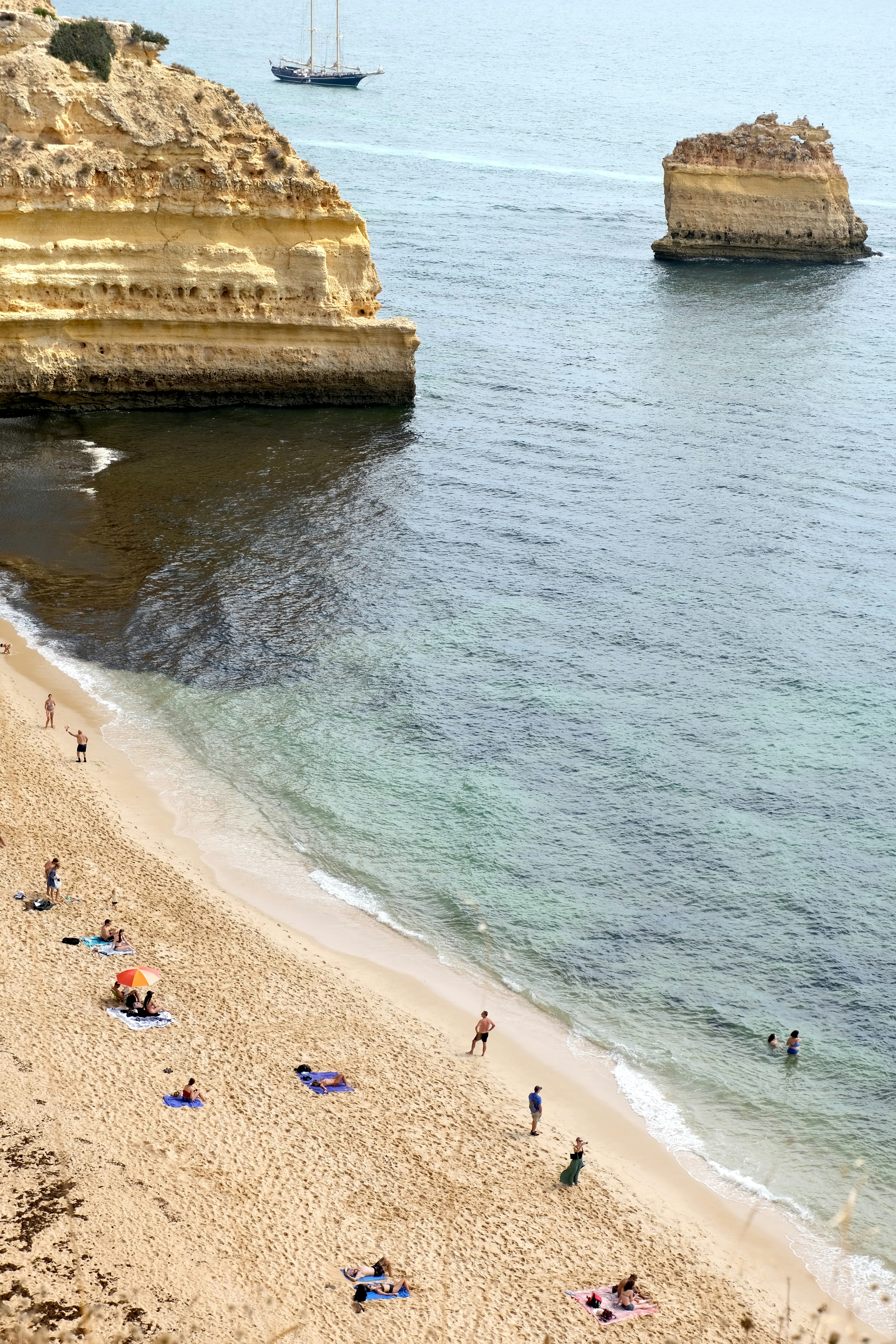 Un groupe de personnes debout au sommet d’une plage de sable