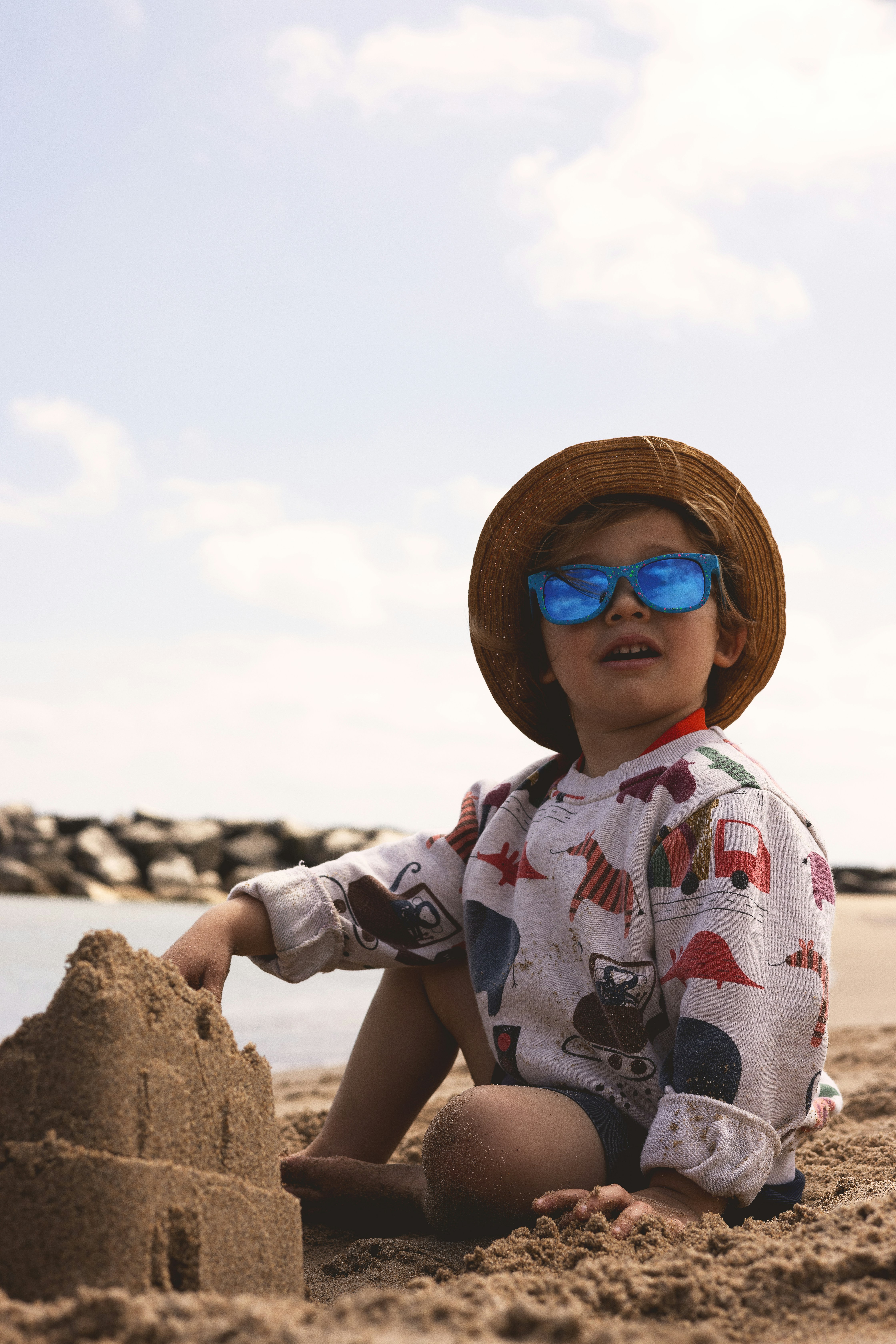 A little boy sitting in the sand at the beach