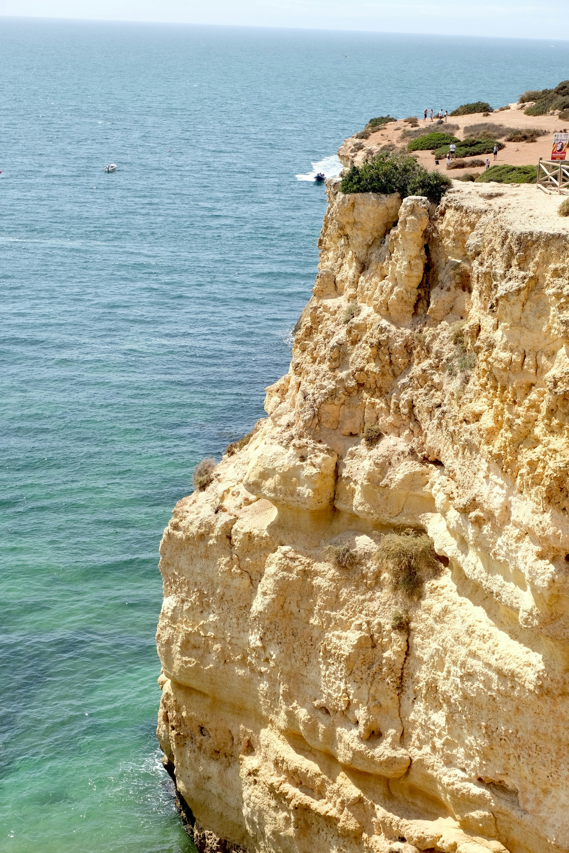 A man standing on top of a cliff next to the ocean