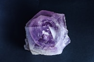 A purple rock sitting on top of a black surface