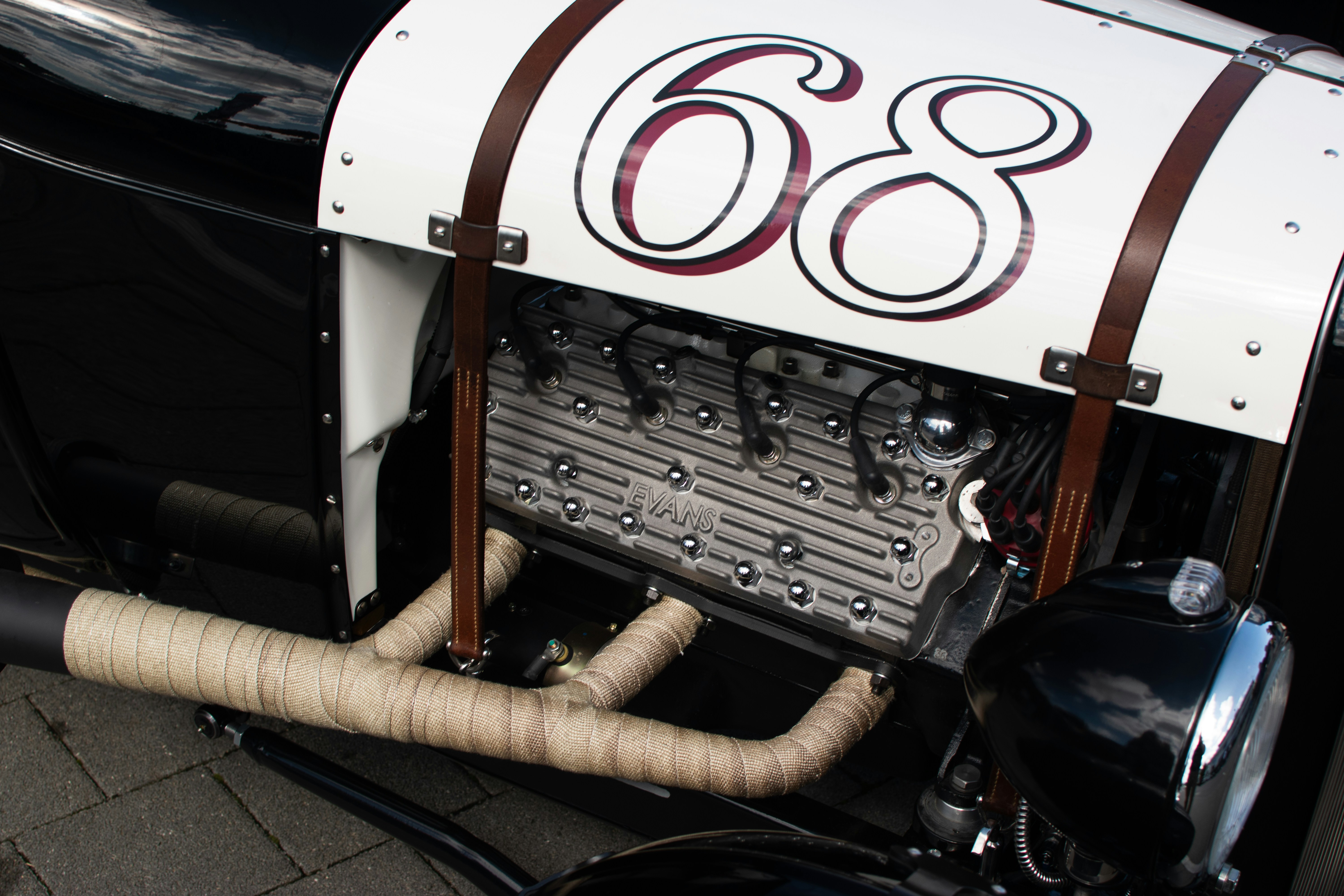 An antique racing car with a V6 engine and the number 68 painted in brown on a white bonnet