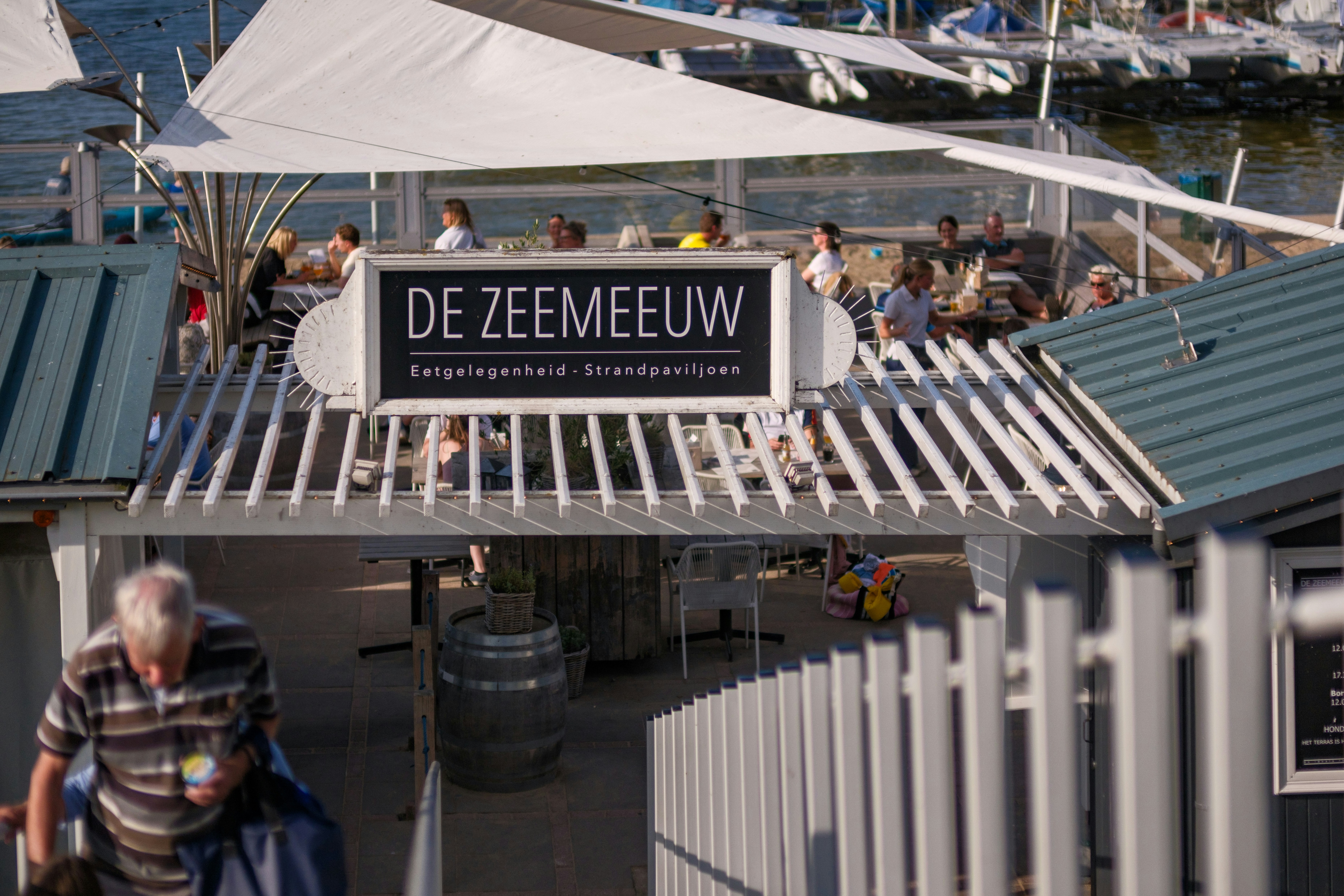 A group of people walking down a street next to a pier
