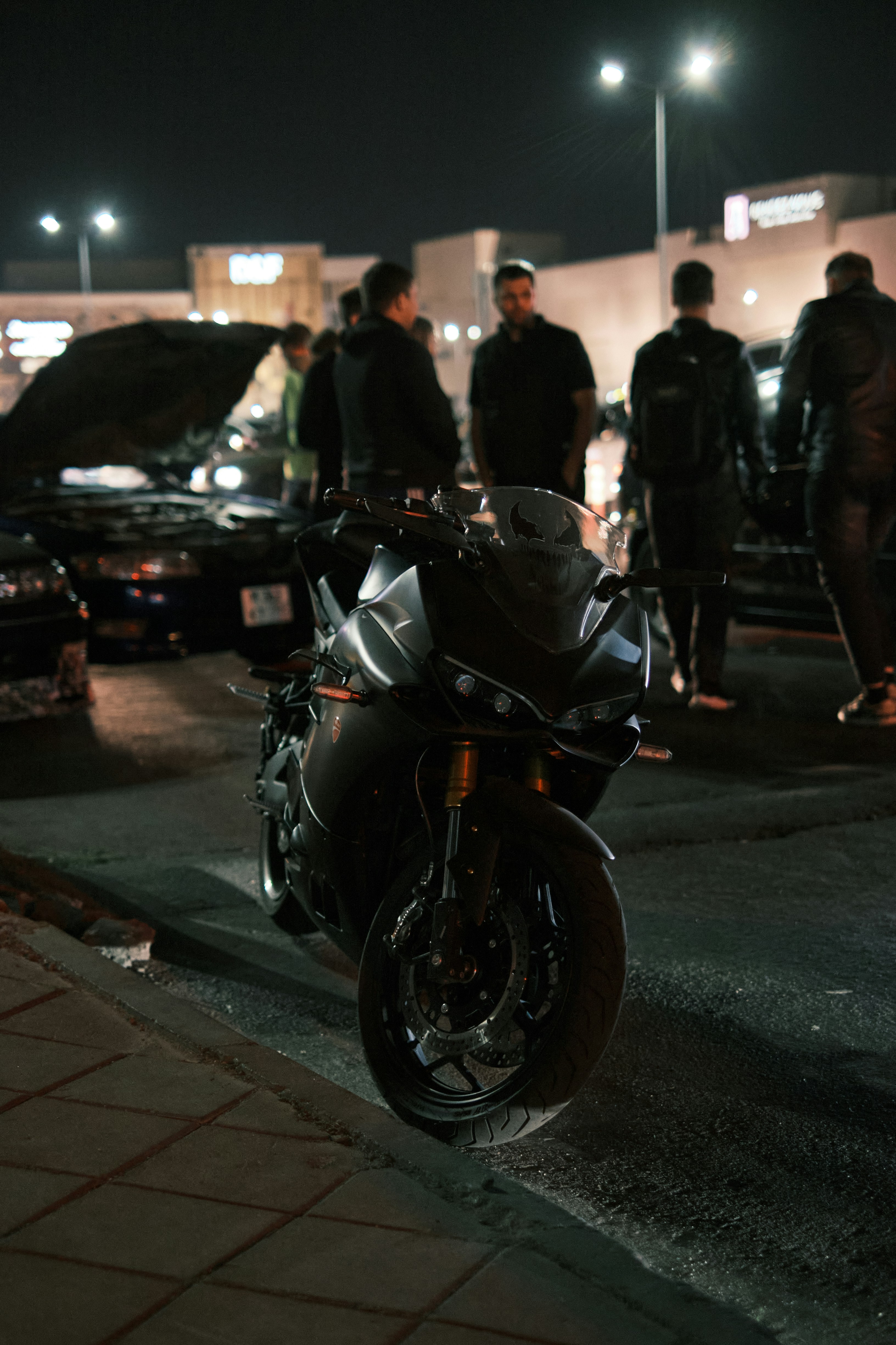 A group of people standing around a parked motorcycle