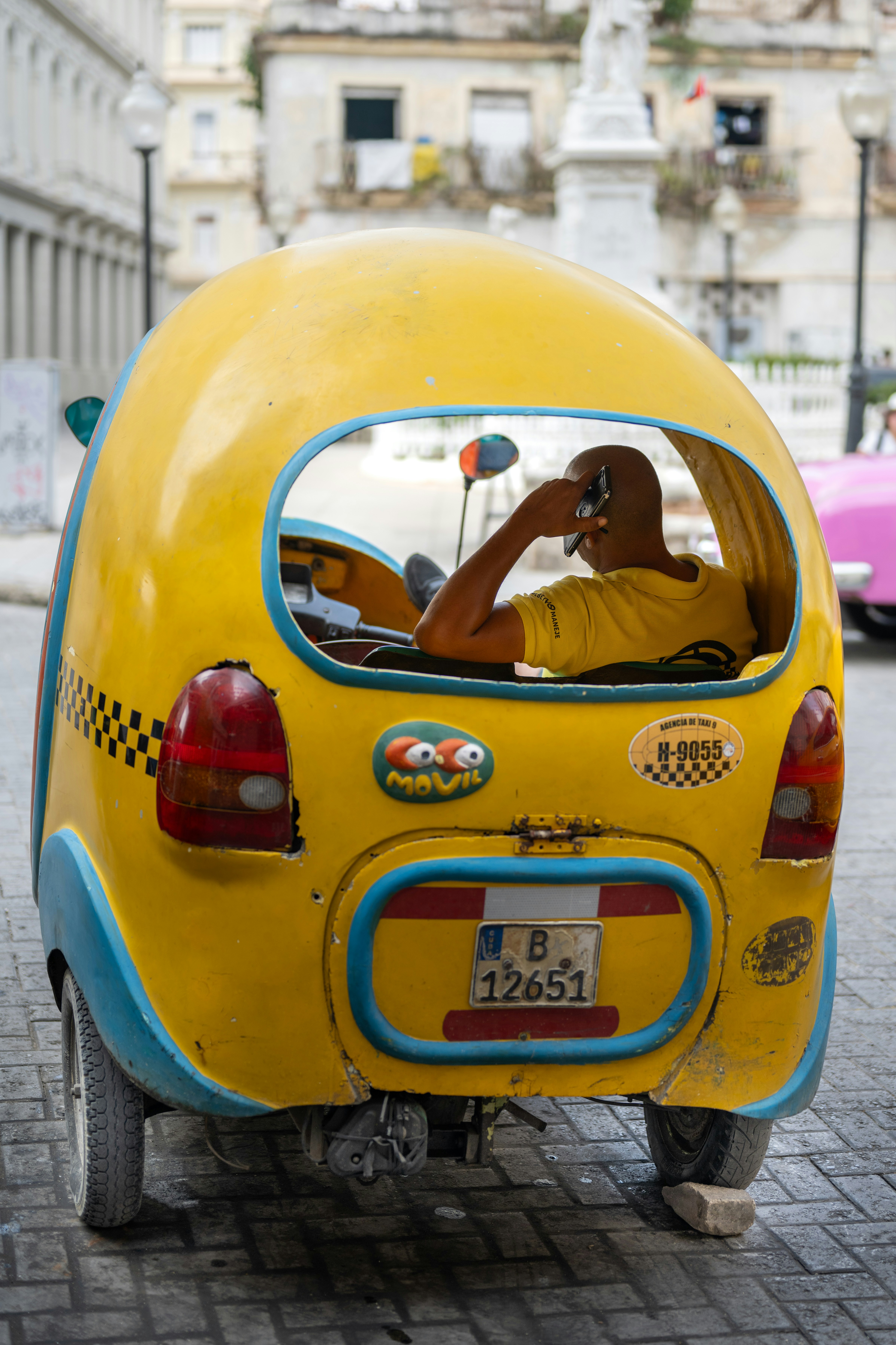 A small yellow car with a man sitting in it